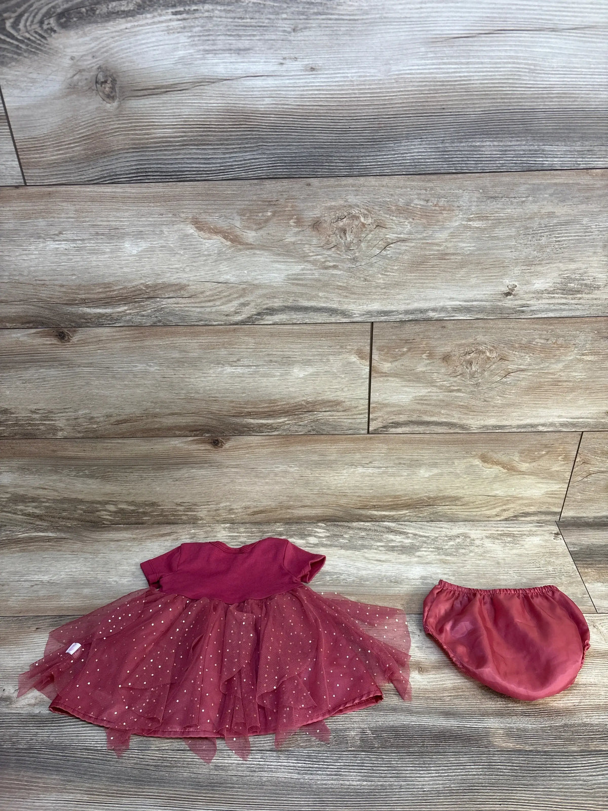 Pink baby dress with sparkling tulle skirt and matching diaper cover on wooden background