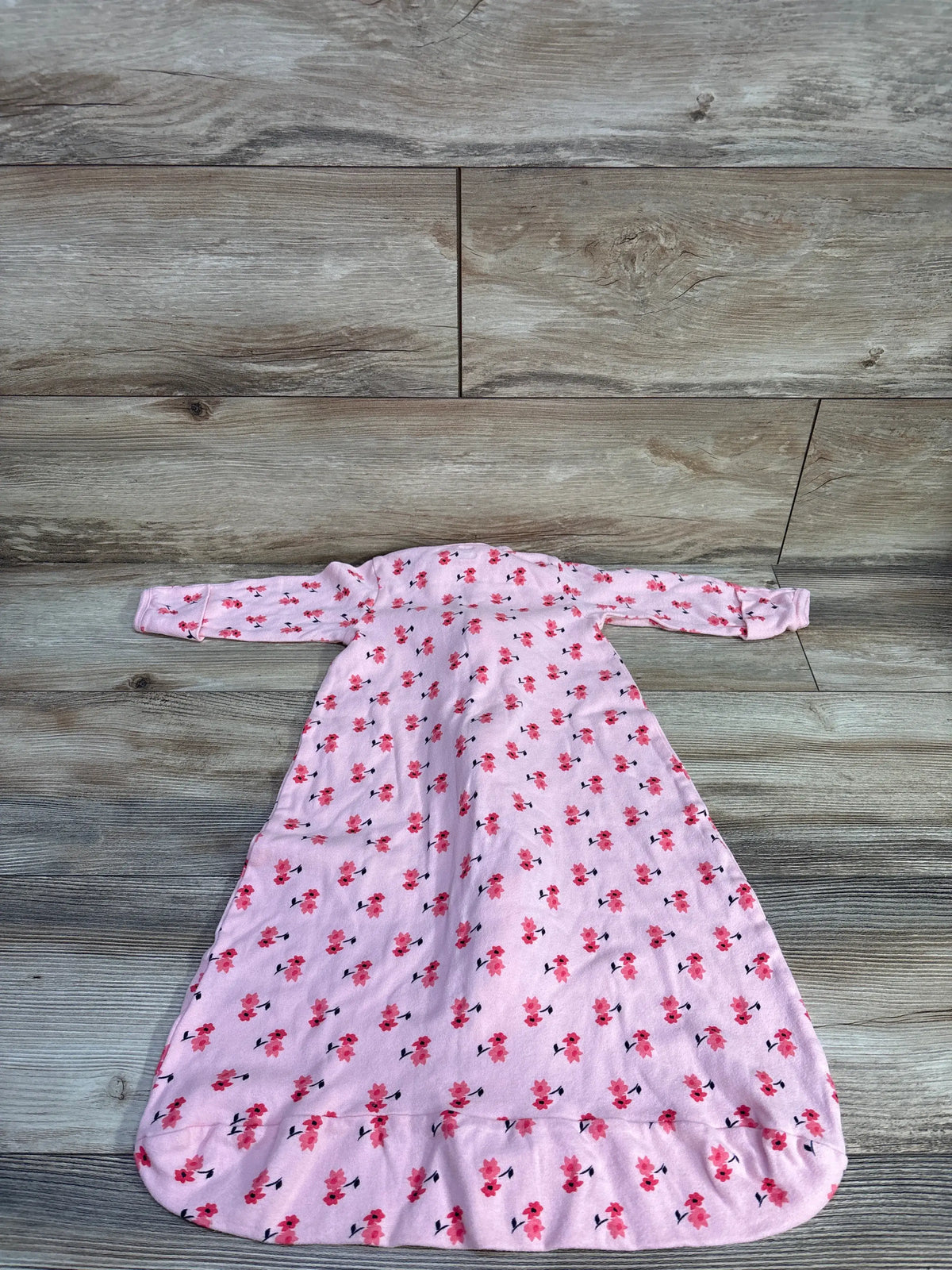 Top view of Touched By Nature floral sleep sack showcasing pink floral print and long sleeves with wood background