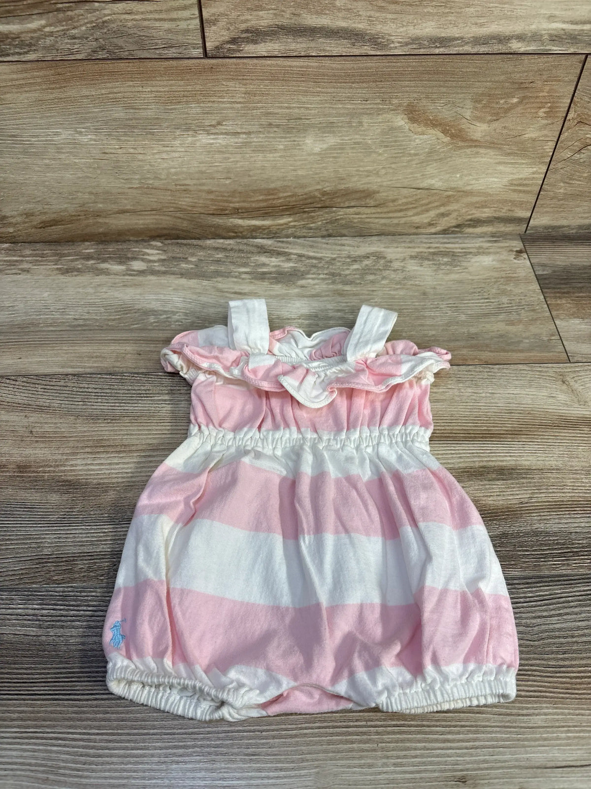 Flat lay of Ralph Lauren romper, pink and white stripes, ruffle collar, elastic waist and legs on wood floor