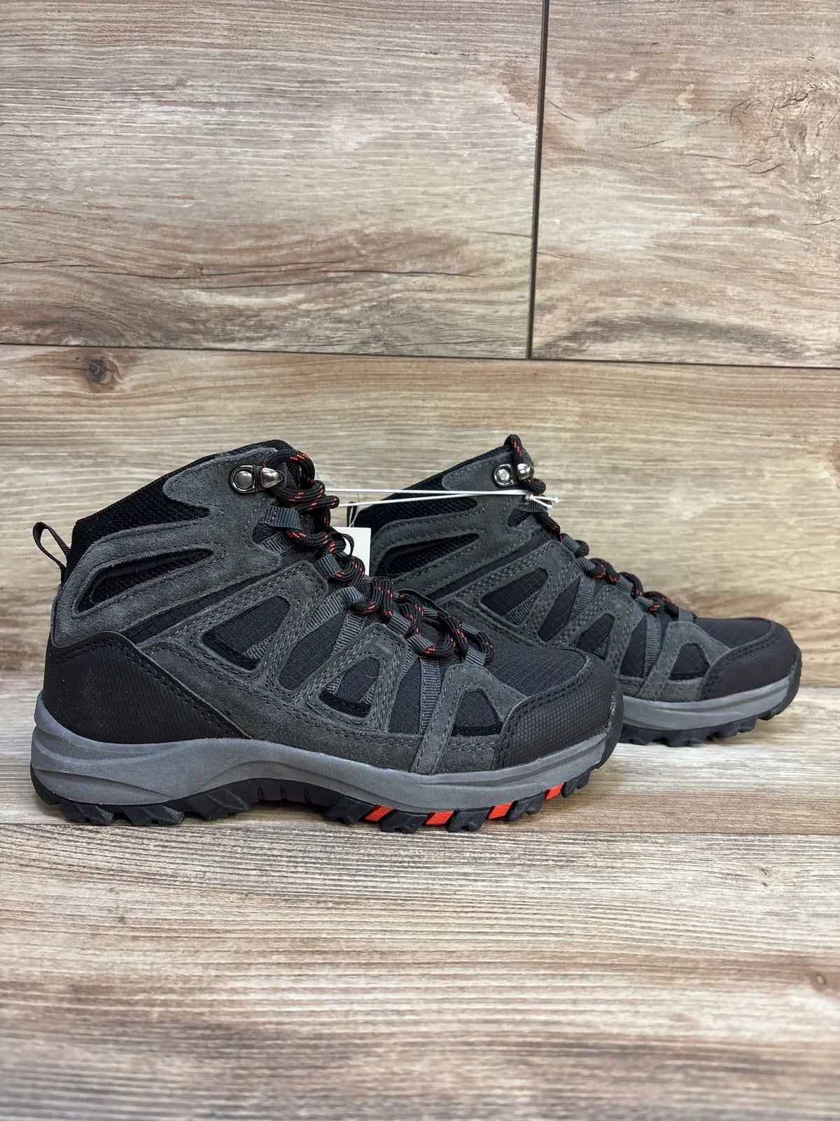 Kids black and gray hiking boots with red accents on wood floor background
