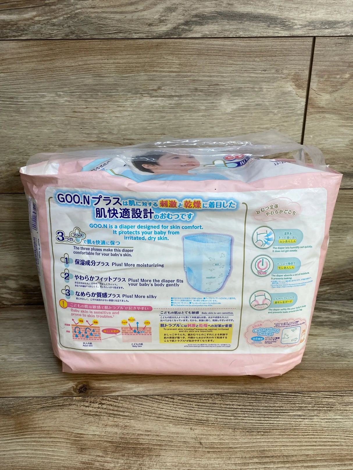 Back view of Elleair Goo.N Plus baby pull-up diaper pants pack (28 count, 28-55 lb) showing packaging text and illustrations on wooden floor