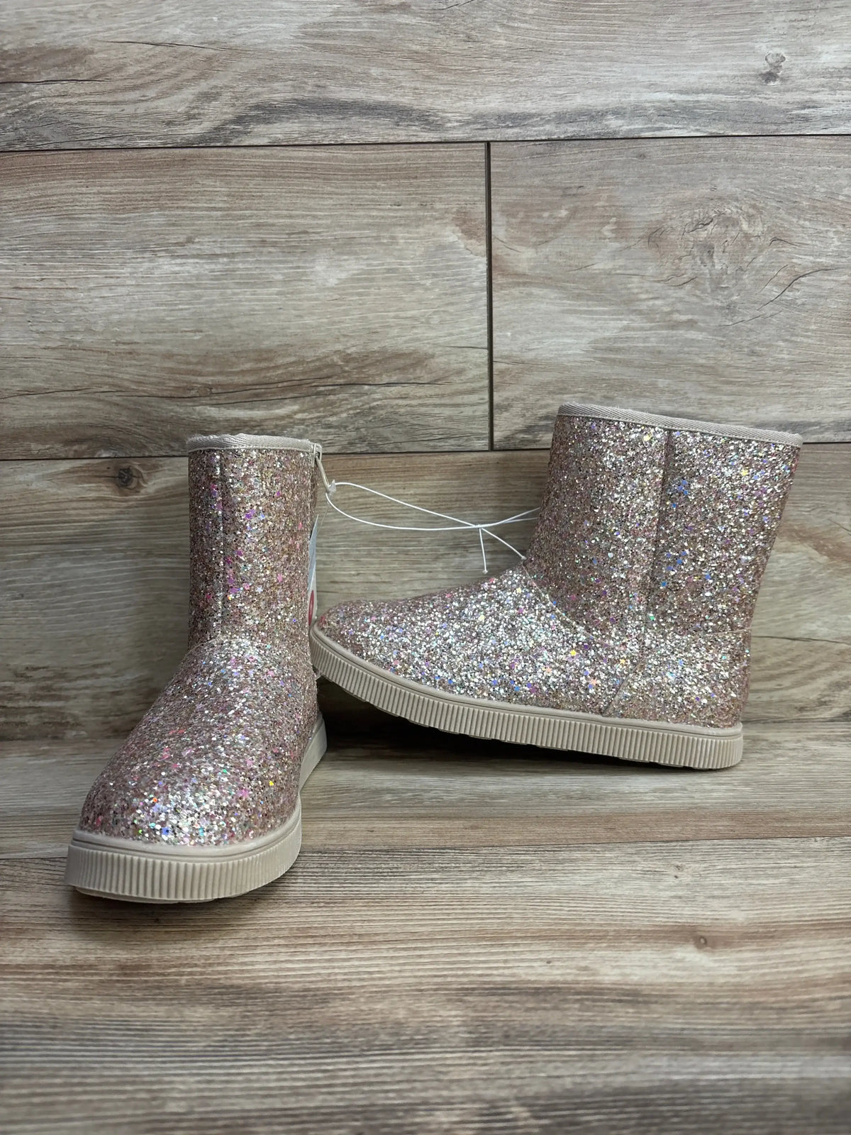 Three-quarter view of Cat & Jack Holland kids shearling-style boots, glittery gold with rubber soles on wooden background