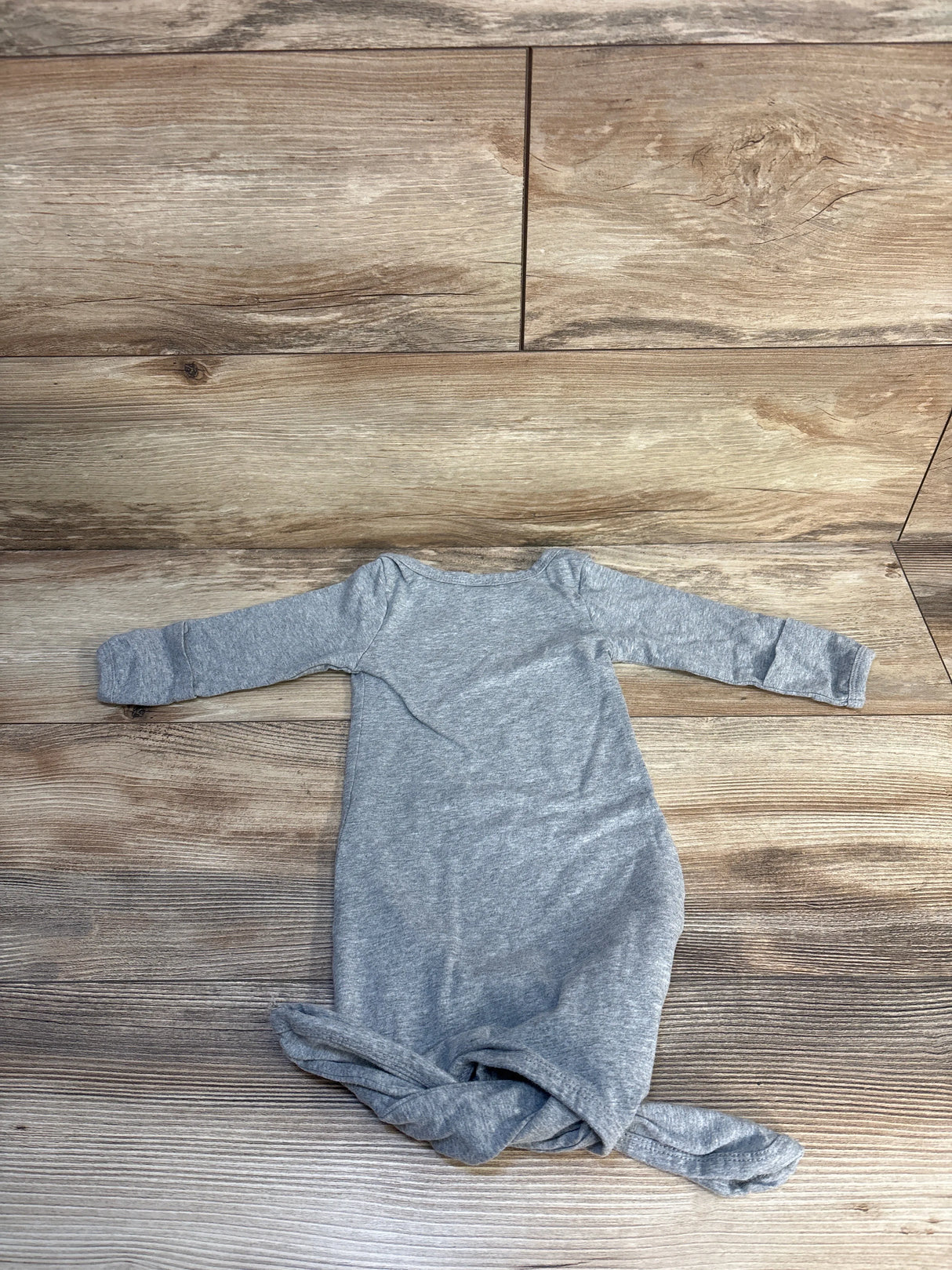 Gray long sleeve baby gown laid flat on wooden floor, gently used infant clothing