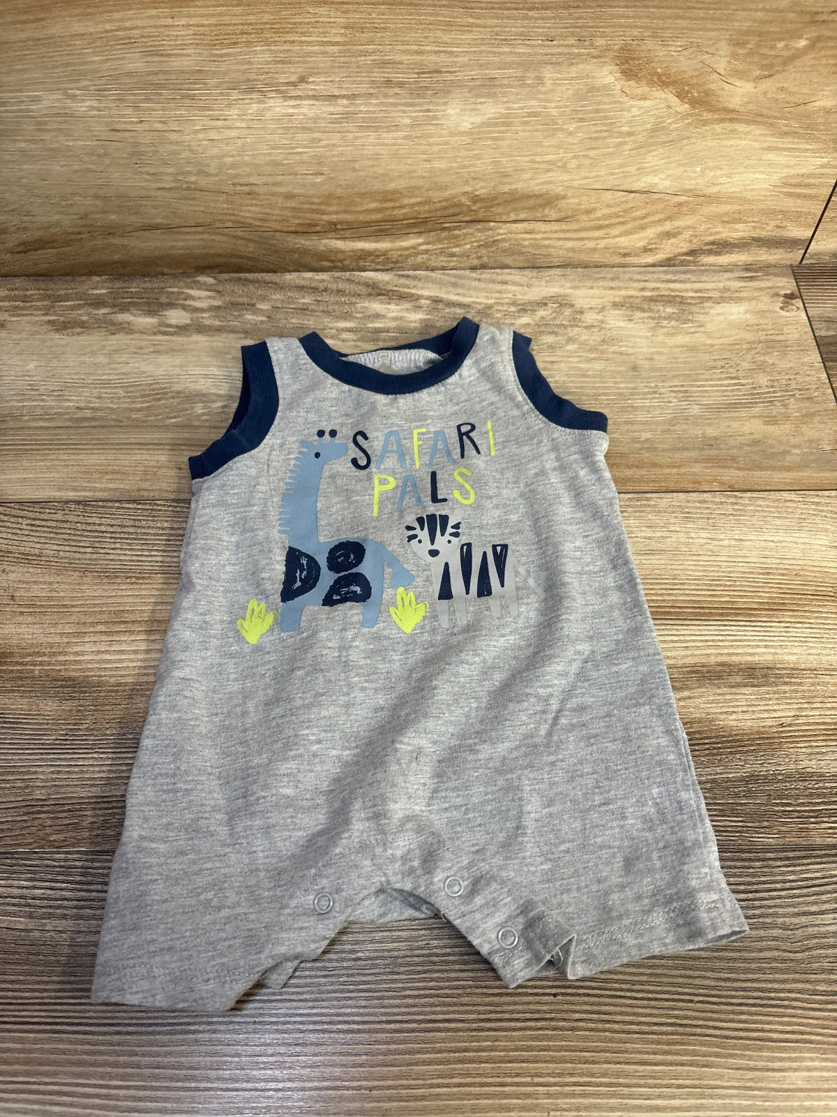 Front view of grey Chick Pea Safari Pals shortie romper with safari animal graphic and navy trim on a wood surface