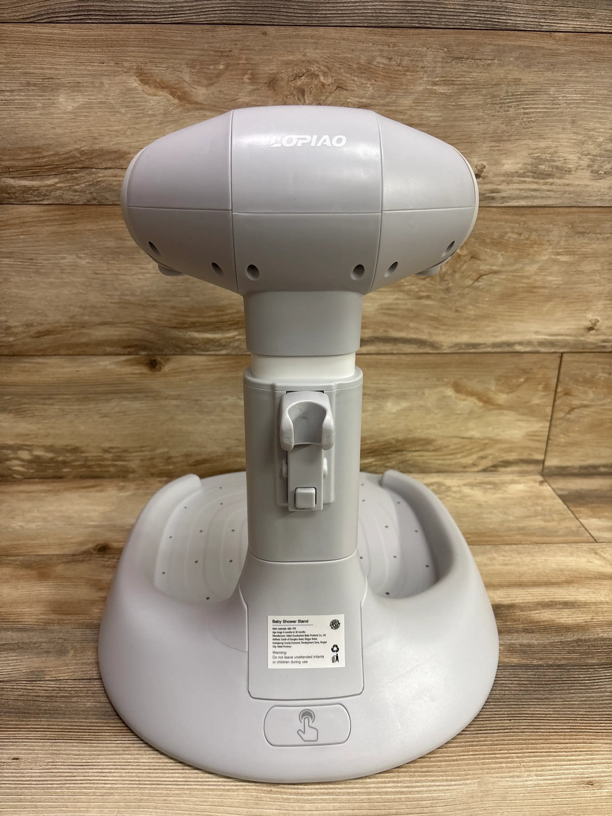 Rear view of Lopiao baby bath stand showcasing its white molded base and central column with a wood background