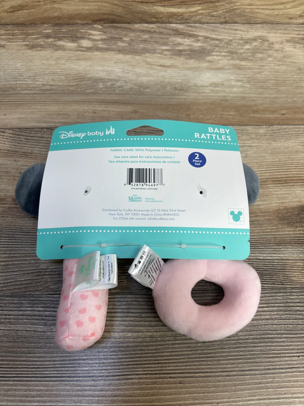 Front view of Minnie Mouse two-pack plush baby rattles: pink donut ring and pink polka-dot rattle on teal backing