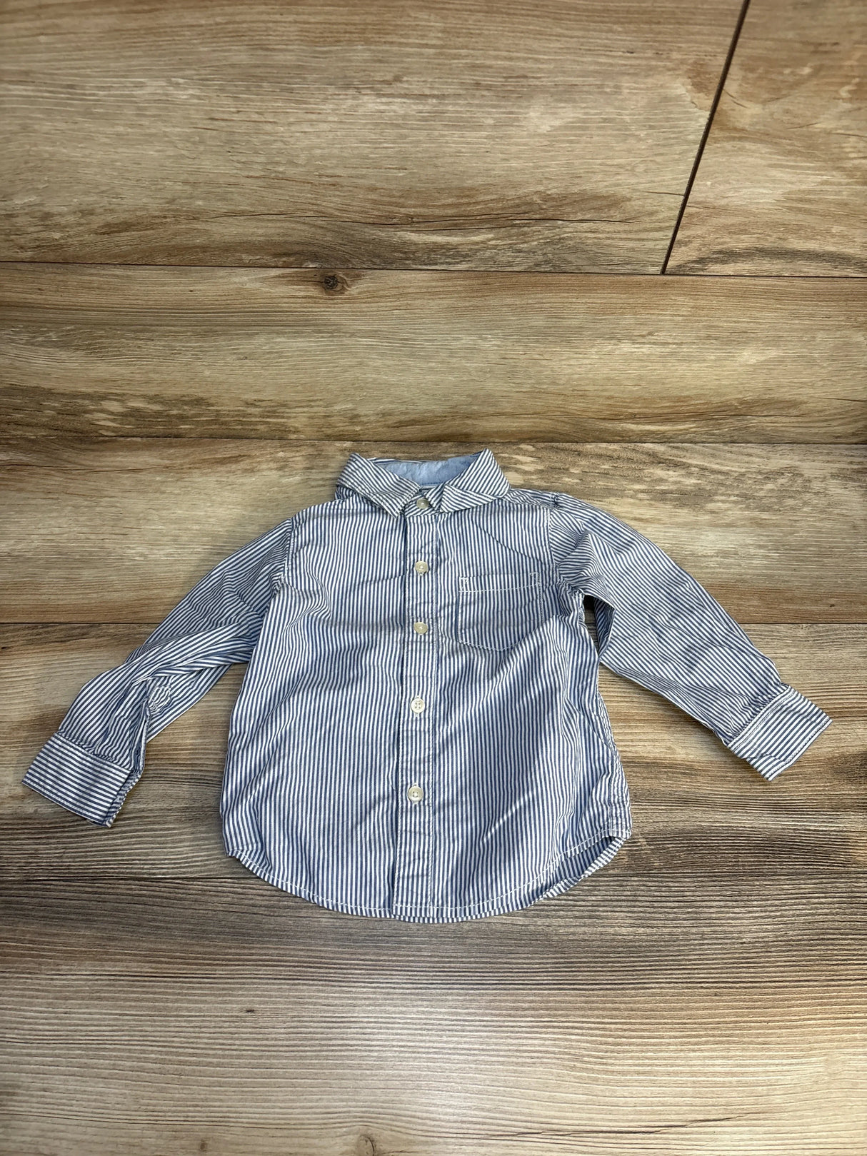Striped long sleeve button-up toddler shirt on wood background