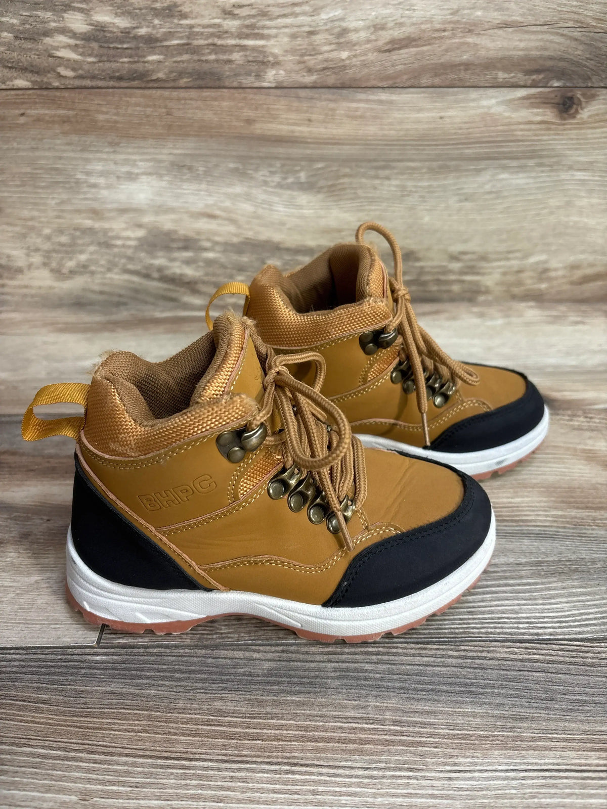 Tan BHPC kids hiking boots with black toe cap and white sole on wooden floor