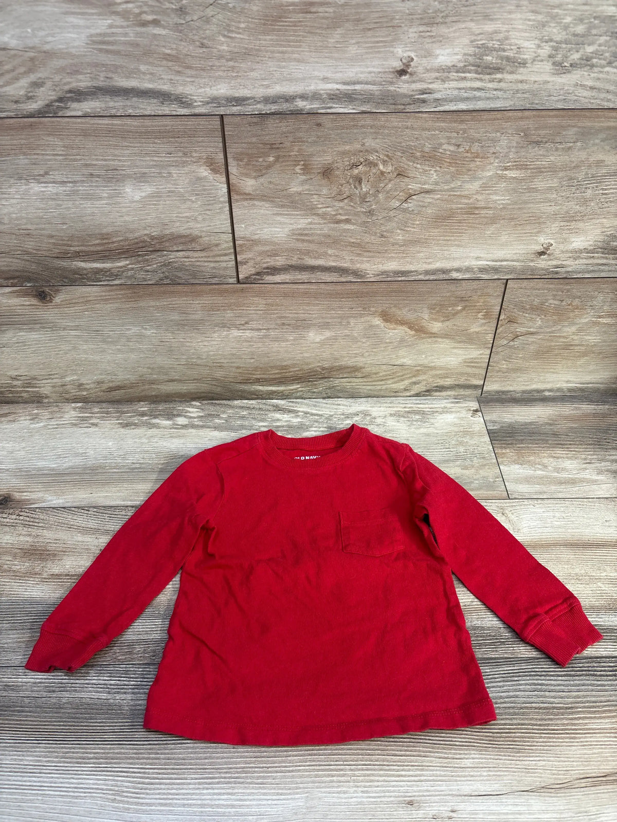 Red long sleeve shirt for toddlers by Me n Mommy To Be laid on a wooden surface