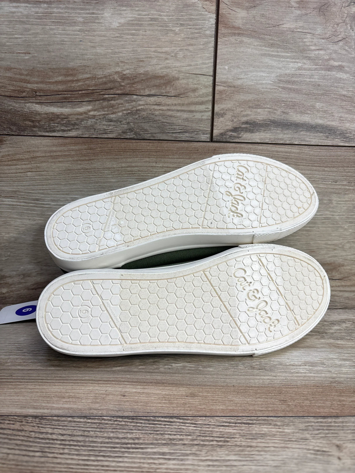 Pair of Cat & Jack white rubber sole shoes size 6 with honeycomb tread pattern on wooden floor