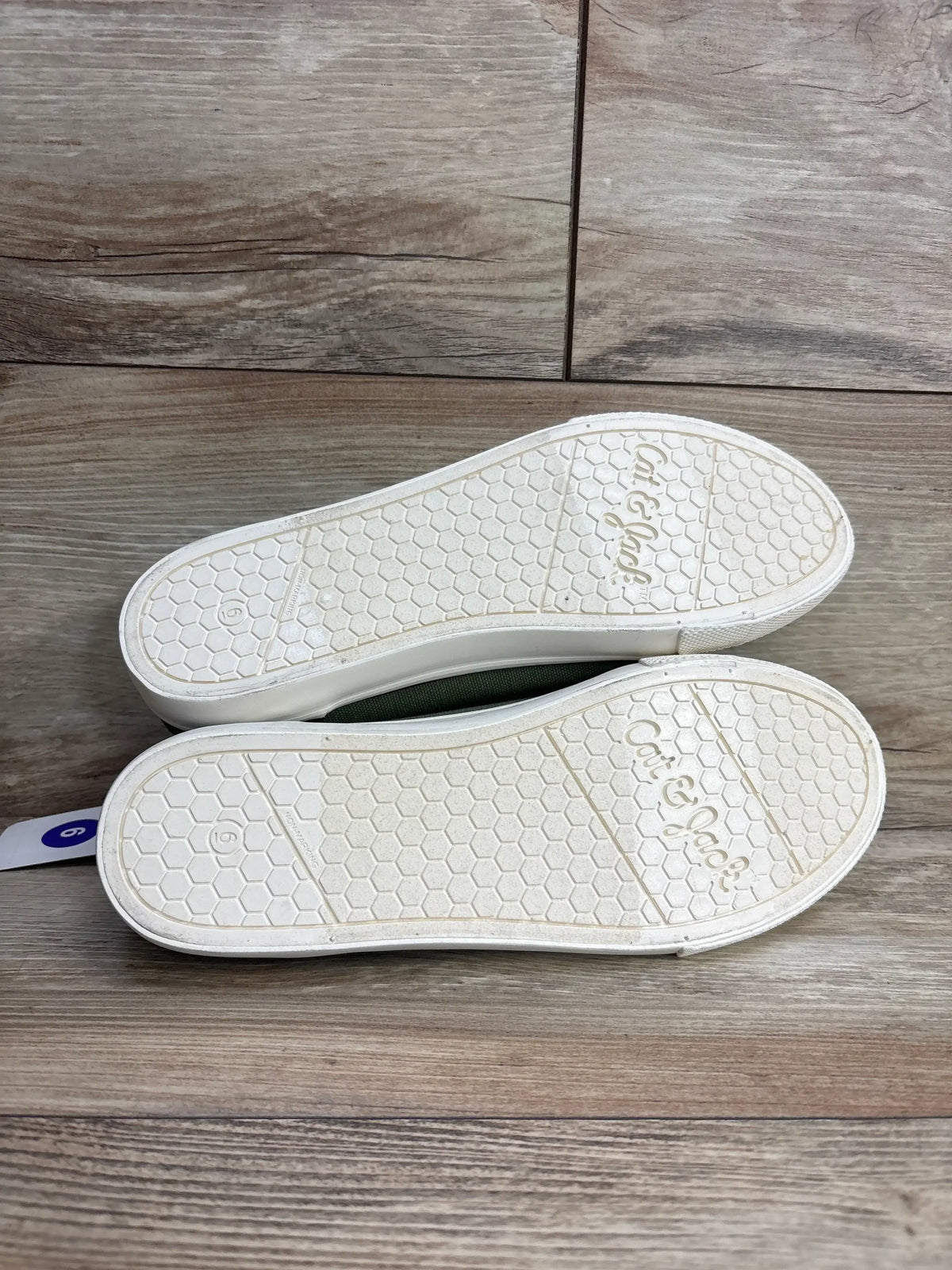 Pair of Cat & Jack white rubber sole shoes size 6 with honeycomb tread pattern on wooden floor