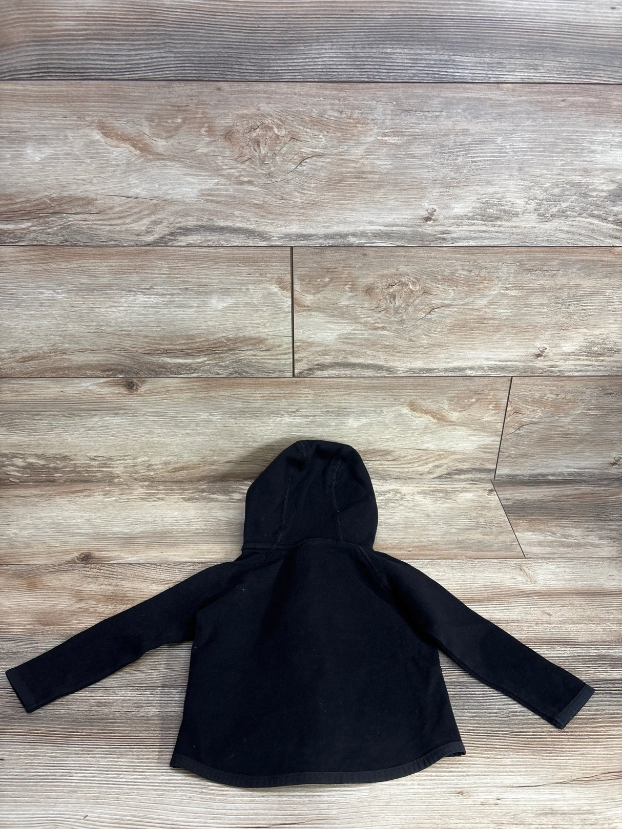 Black long sleeve kids hoodie laid flat on wooden background