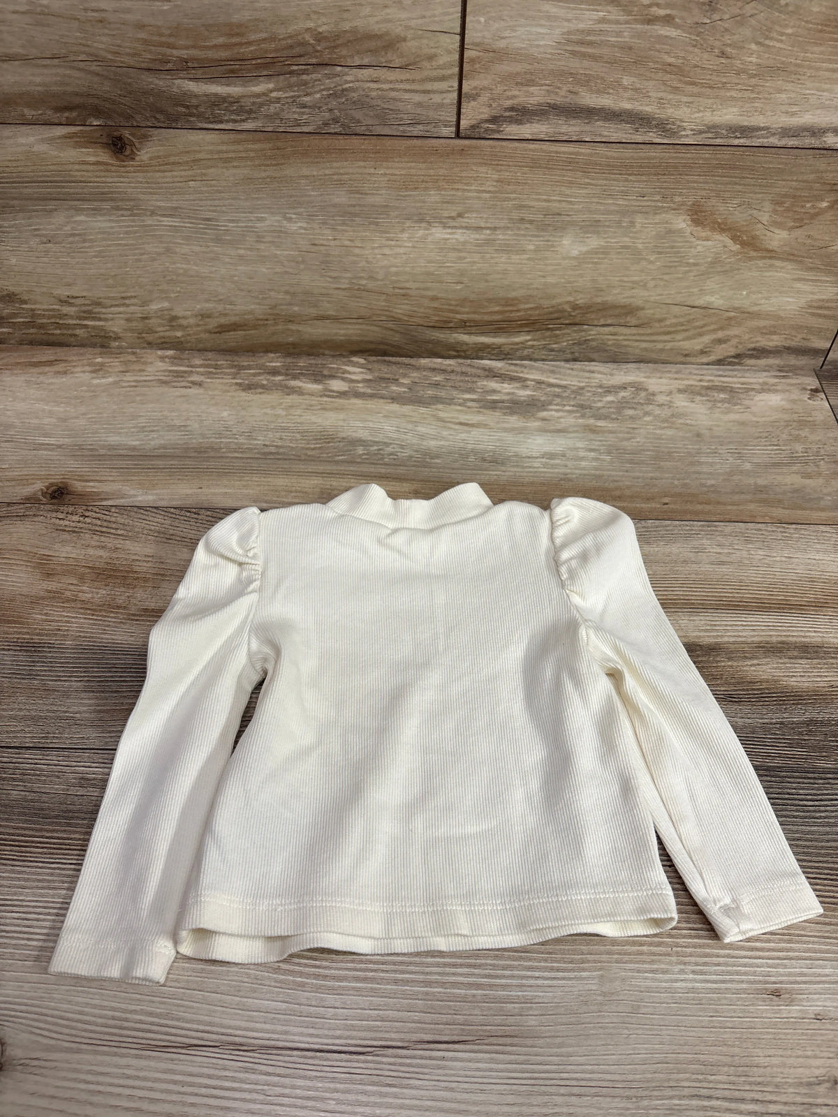 Baby Gap ivory ribbed long sleeve shirt with puffed shoulders on a wooden background