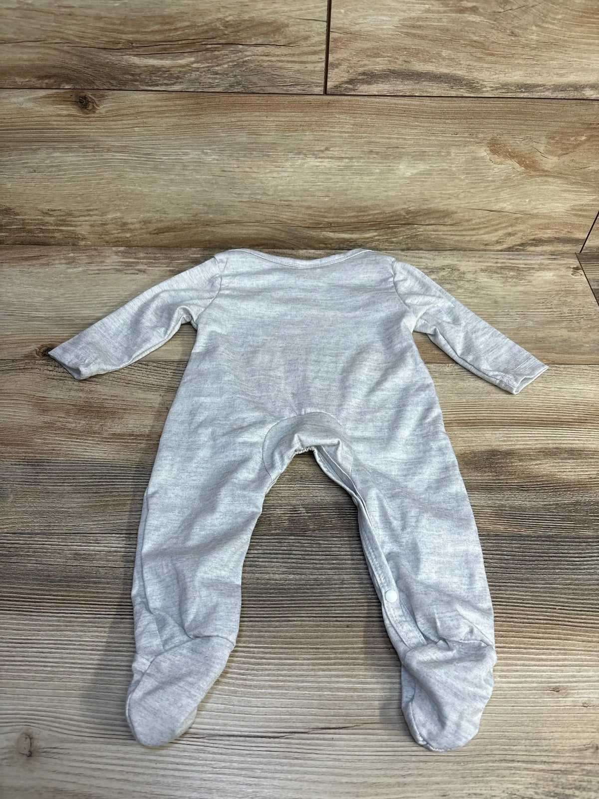 Back view of Moon and Star Footed Coverall in heather grey long sleeve with snap closures on wood plank floor