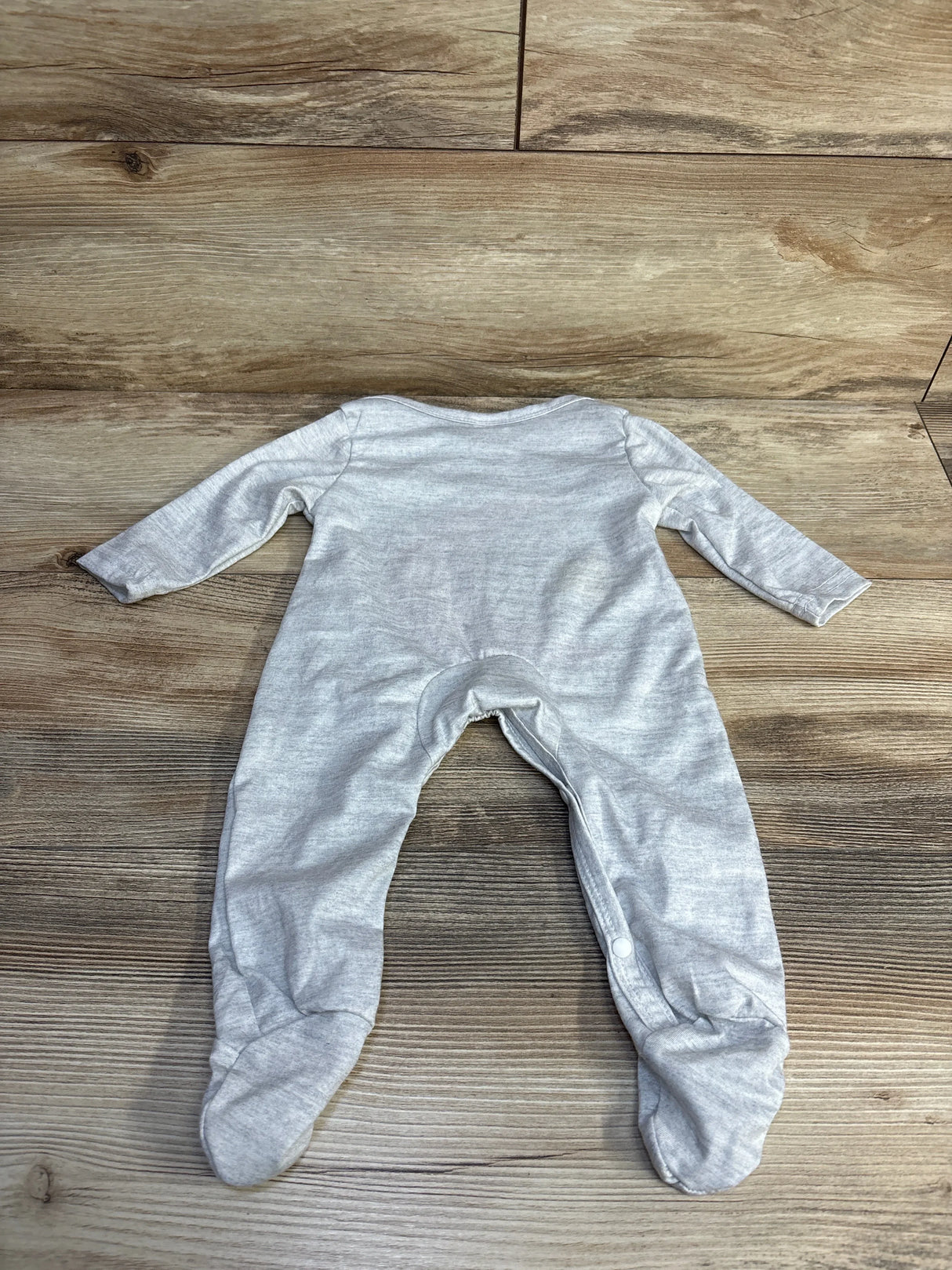 Back view of grey moon and star footed coverall showing long sleeves, built-in feet, and snap leg closure on wood backdrop