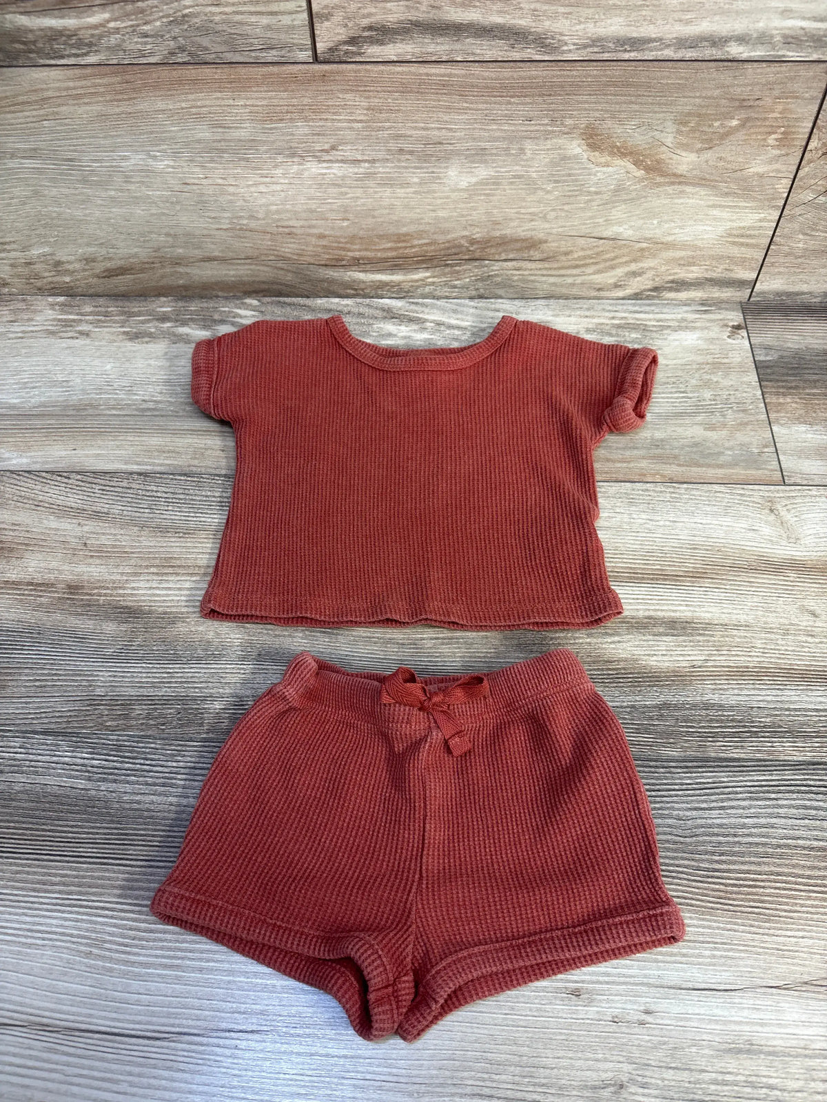 Front view of Cat & Jack two-piece waffle knit shirt and matching shorts set in warm rust, laid flat on wood background