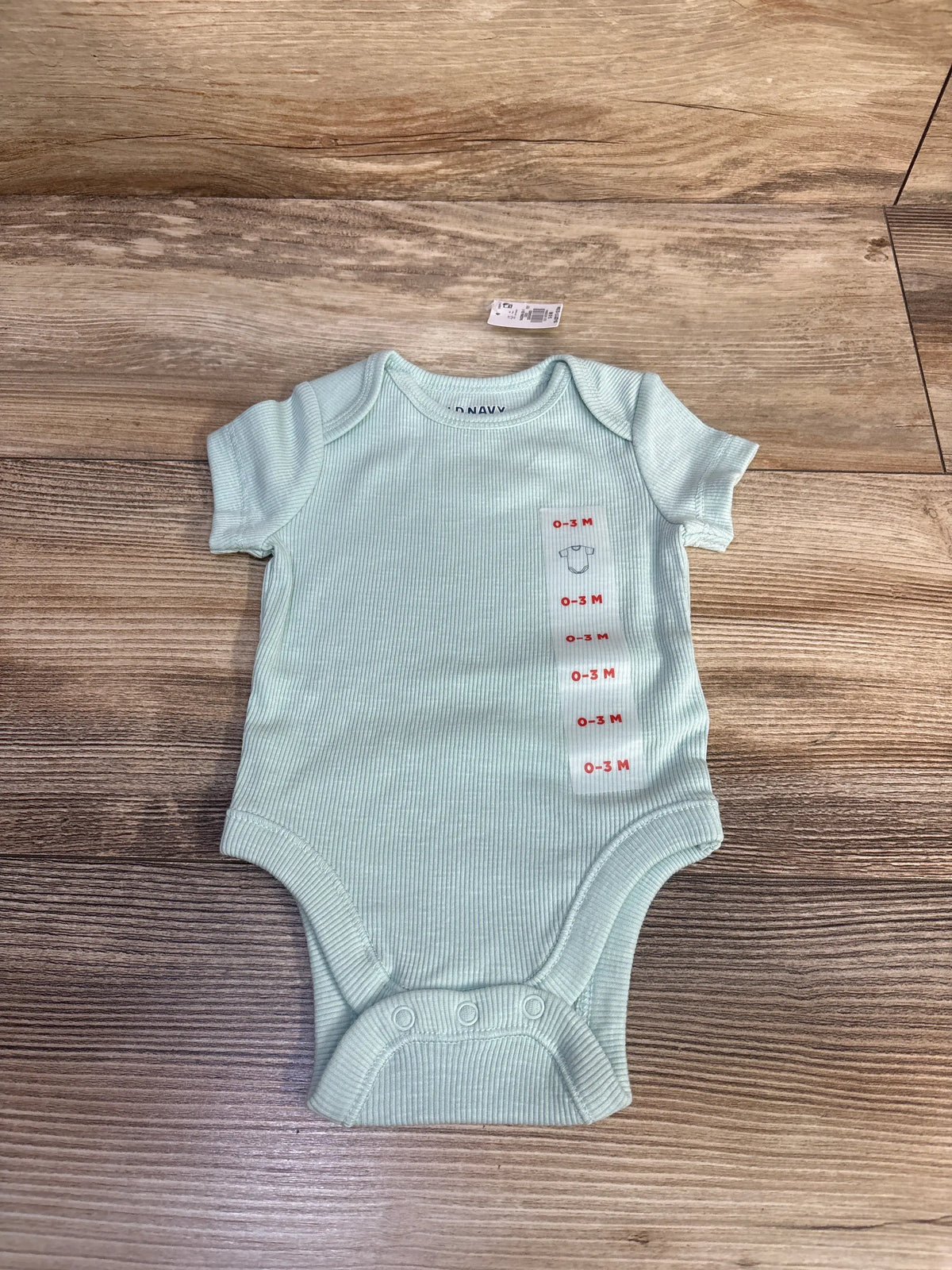 New Baby Gap ribbed bodysuit in mint green, size 0-3 months, on a wooden background.