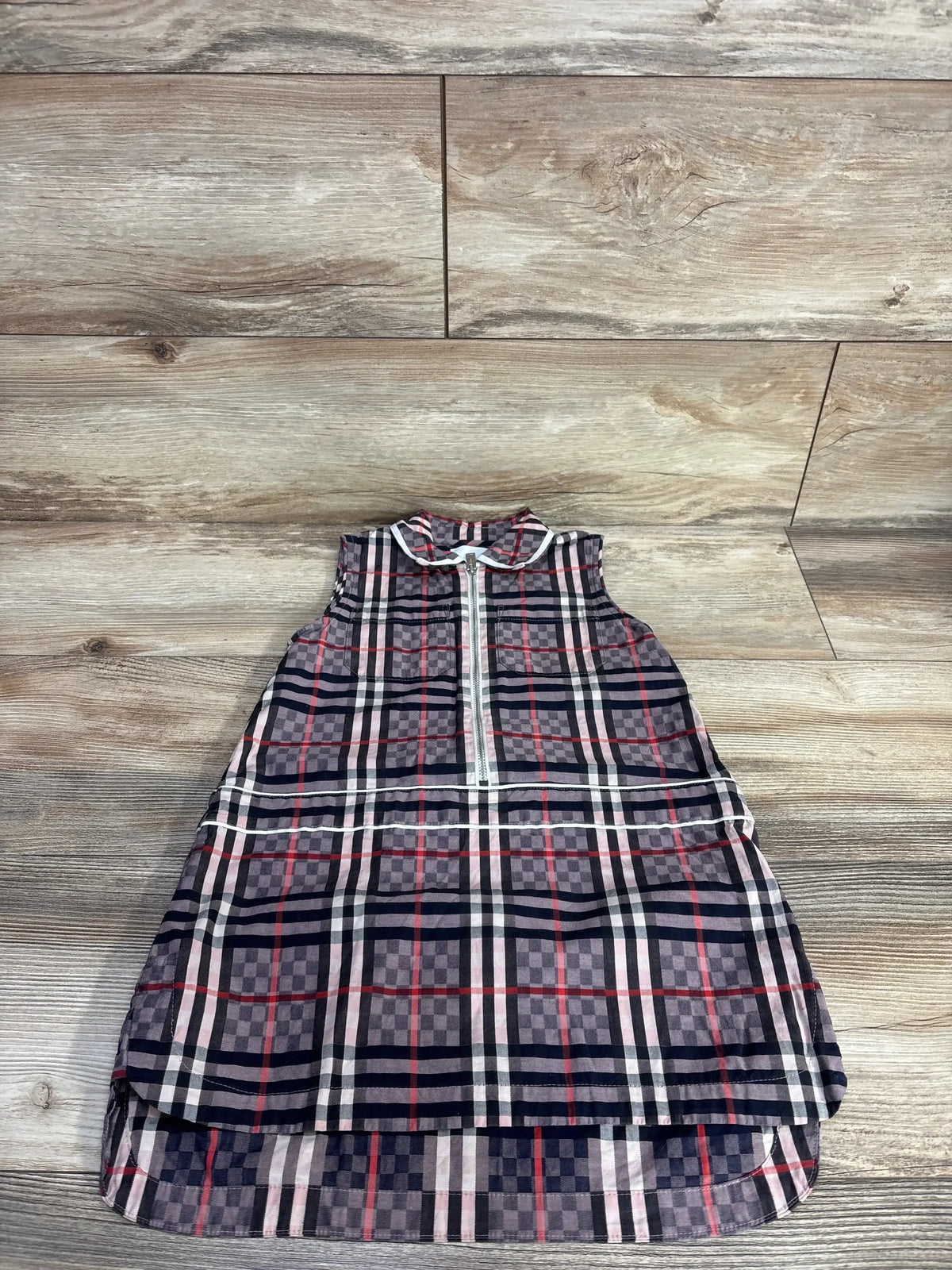 Flat-lay of Burberry Carlotta checked sleeveless dress (4T) showing front zipper and Peter Pan collar on wood background