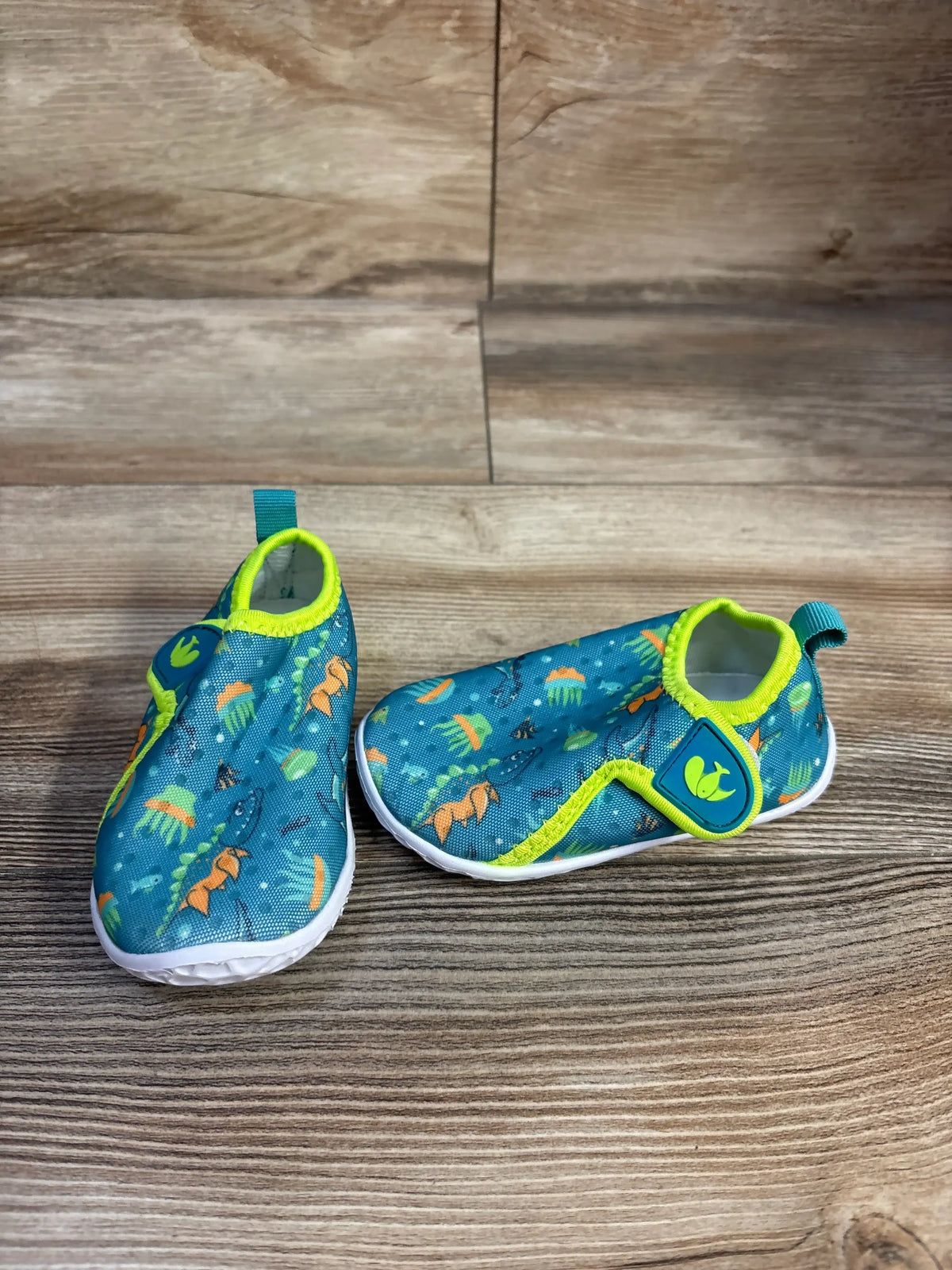 Front and side views of FEETCITY wide barefoot water shoes showcasing teal patterned uppers, lime trim, and straps on wood