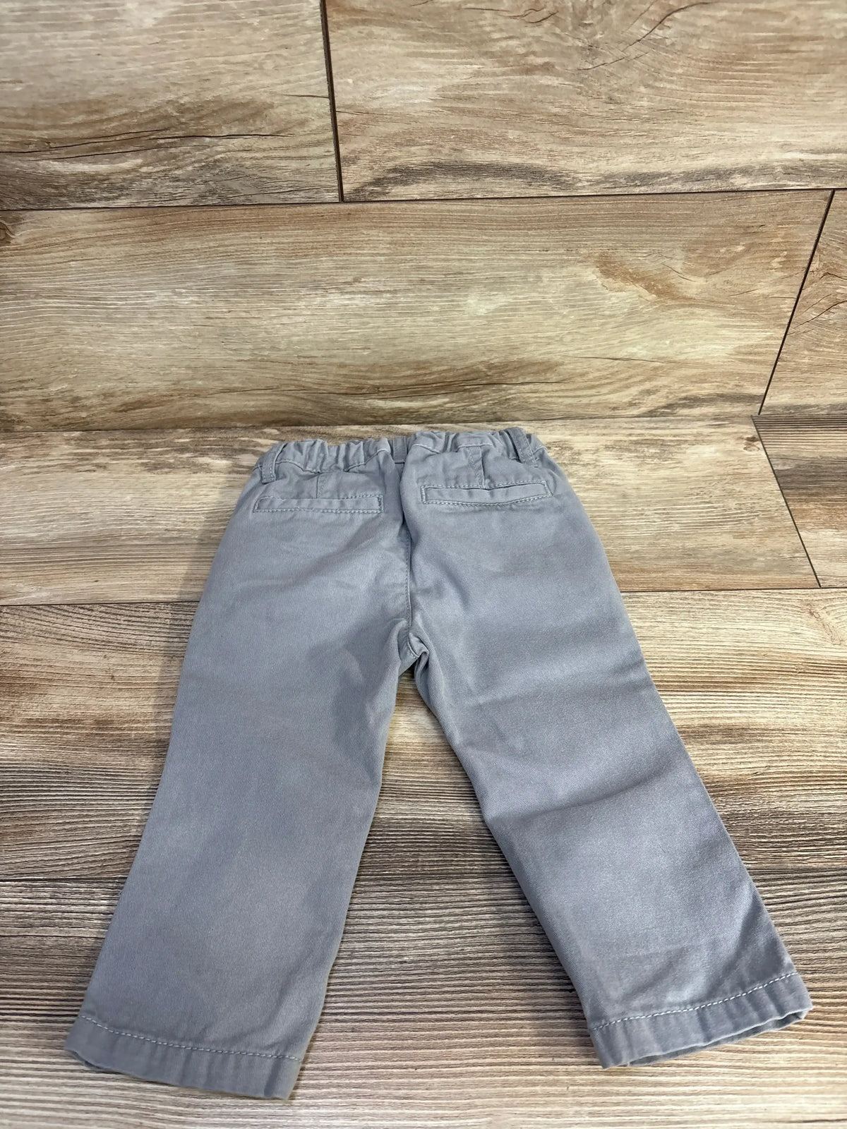 Back view of Children’s Place grey jeans size 12 to 18 months, showing back pockets and adjustable waistband on wood flooring