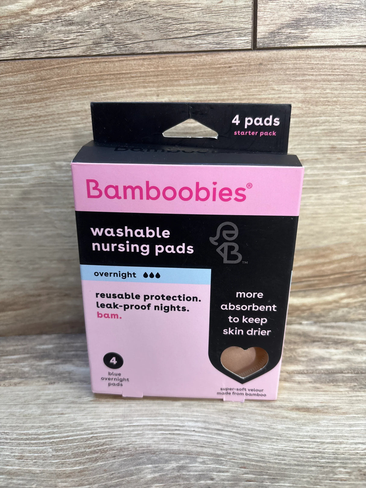 Front of Bamboobies overnight washable nursing pads 4-pack box with pink design and heart window showing pad on wood floor