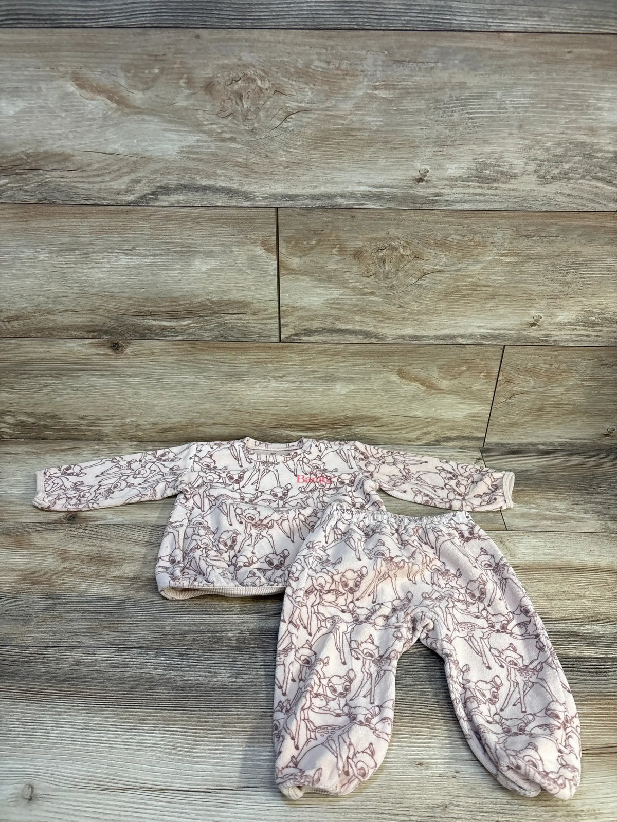 Top-down view of H&M x Disney Bambi sweatshirt set showcasing beige velvet deer print on wood flooring