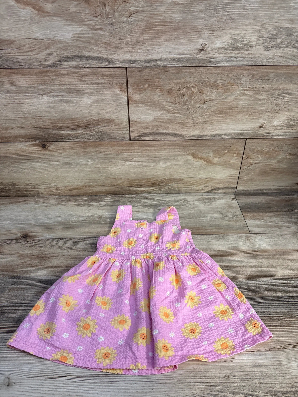 Front view of Little Lass textured dress in pink, size 24 months, showcasing floral print and gathered skirt on wood-look floor