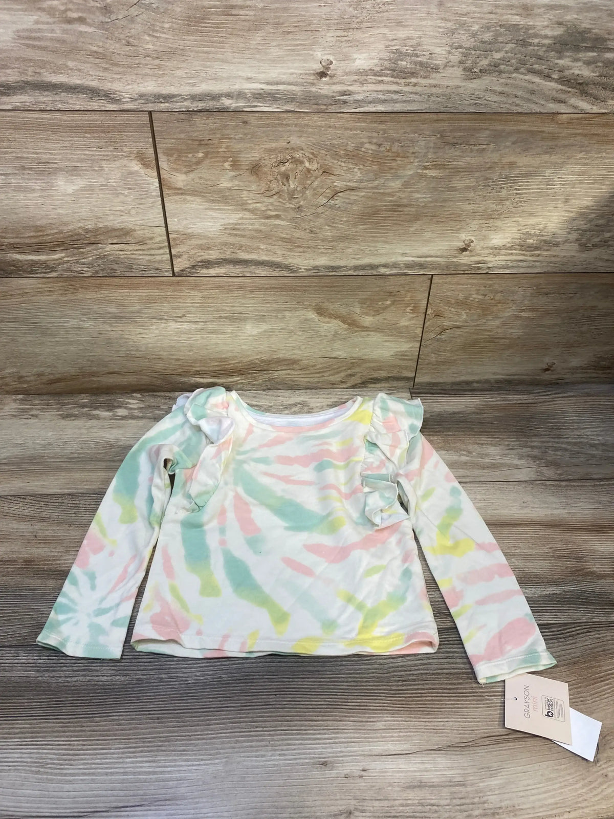 Pastel tie-dye long sleeve toddler shirt with ruffle shoulders on wood background