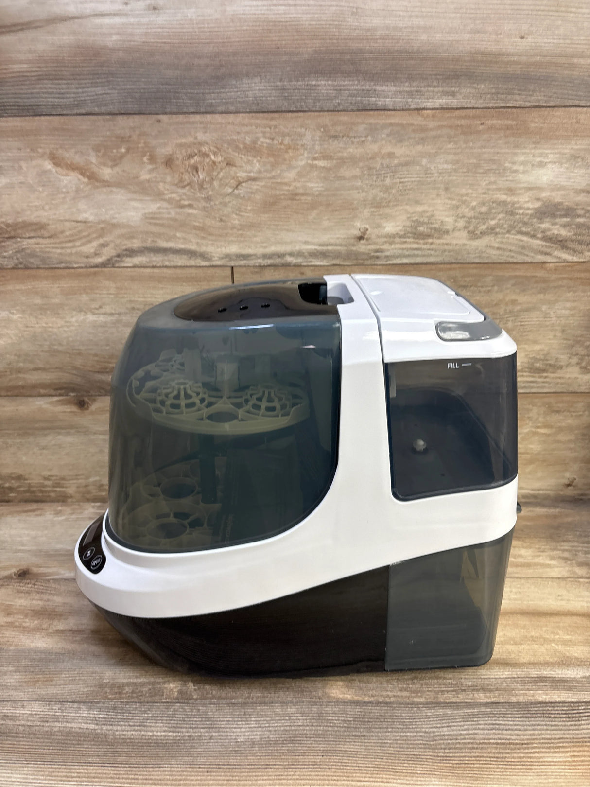 Side view of Baby Brezza Bottle Washer Pro showing translucent lid, bottle racks, and side water tank on wood background