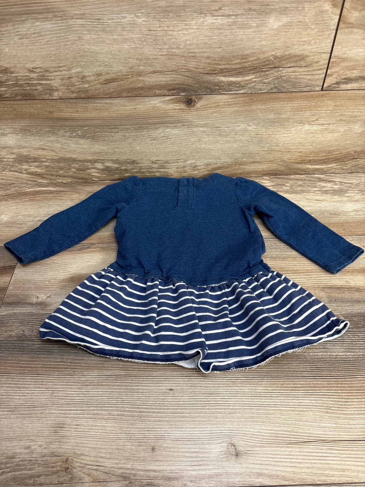 Flat lay of Mud Pie dress showing long-sleeve navy knit bodice and navy-and-white striped skirt on wood background