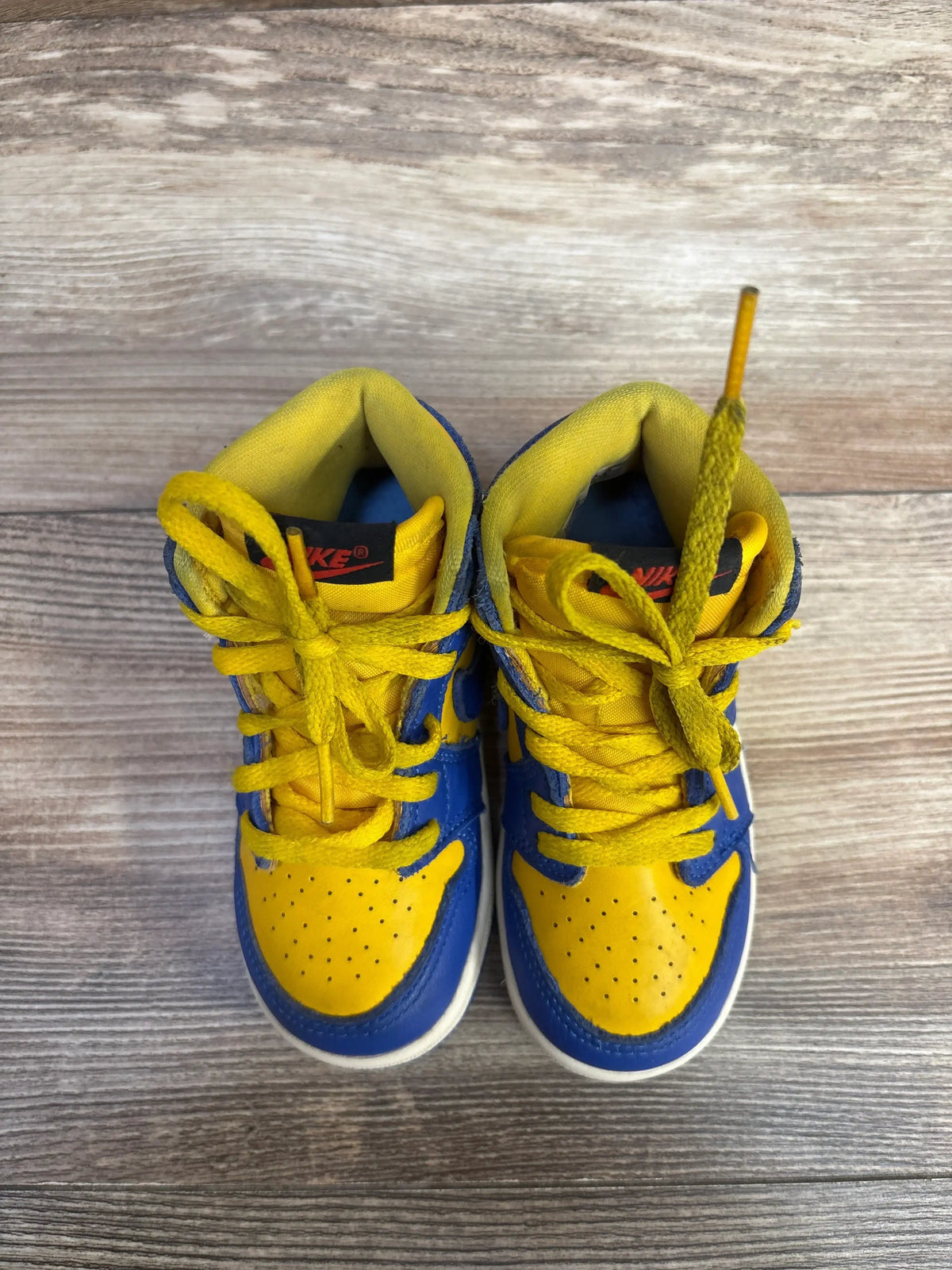 Top view of Air Jordan 1 Retro High OG TD Reverse Laney sneakers showing Varsity Maize and Game Royal leather uppers on wood