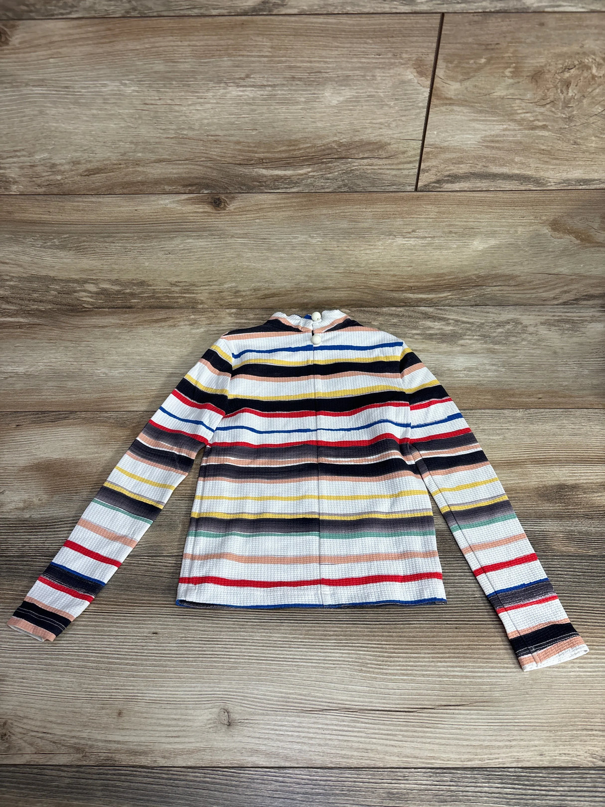 Long sleeve children's top with multicolor horizontal stripes on wooden floor