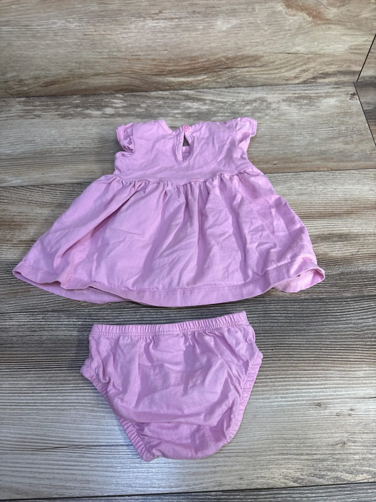 Front view of Carter’s pink two-piece dress and bloomers set with short sleeves and gathered skirt on wood flooring
