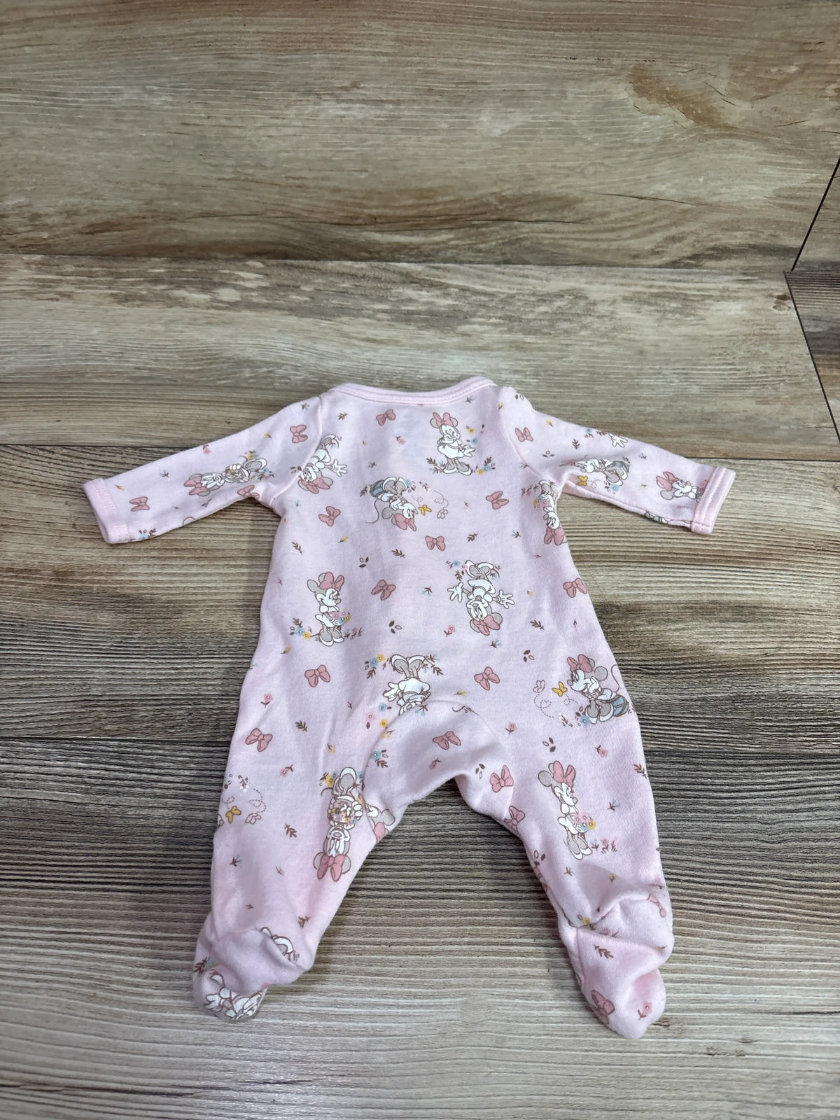 Pink Disney Baby Minnie Mouse preemie sleeper with all-over print on a wooden background