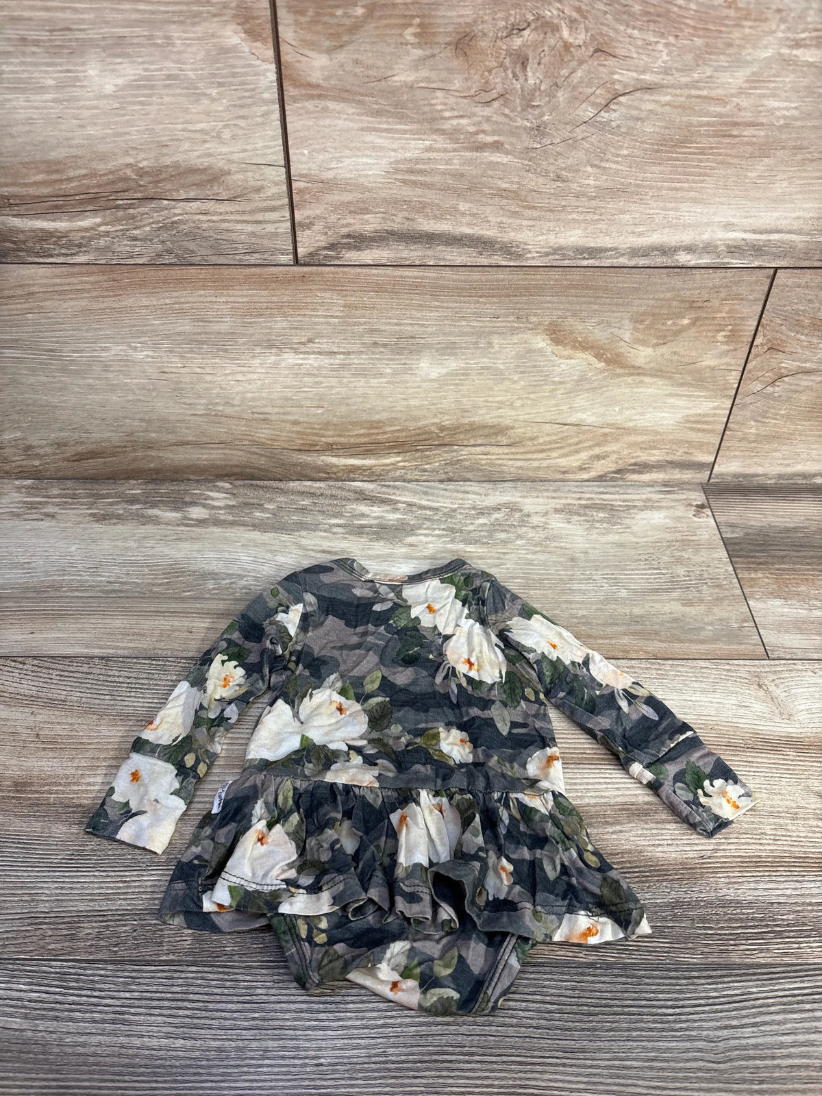 Front view of Gigi and Max bamboo tutu bodysuit showcasing floral camo print and layered tutu skirt on a wood floor