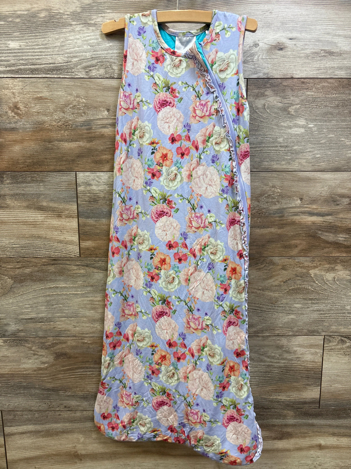 Front view of Posh P. 0.5 TOG bamboo sleeveless sleep sack showcasing a lilac floral pattern and front zipper on wood