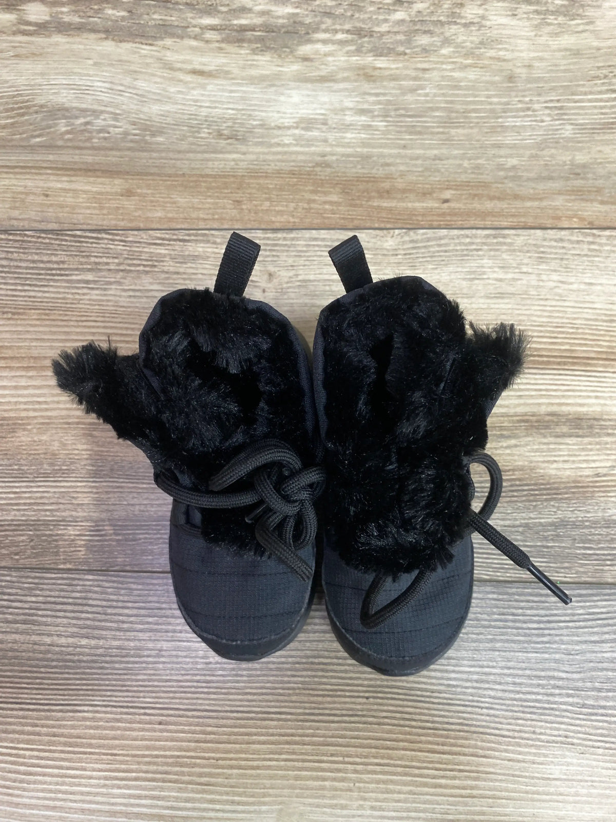 Top view of Nike Roshe One High TDV black winter boots showcasing fuzzy lining and laces on a wood-grain background