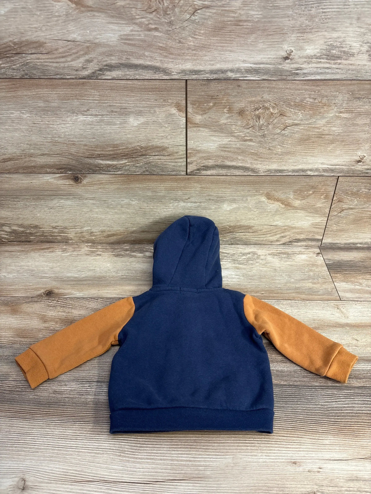 Navy blue and brown toddler hoodie with hood, laid flat on wood floor