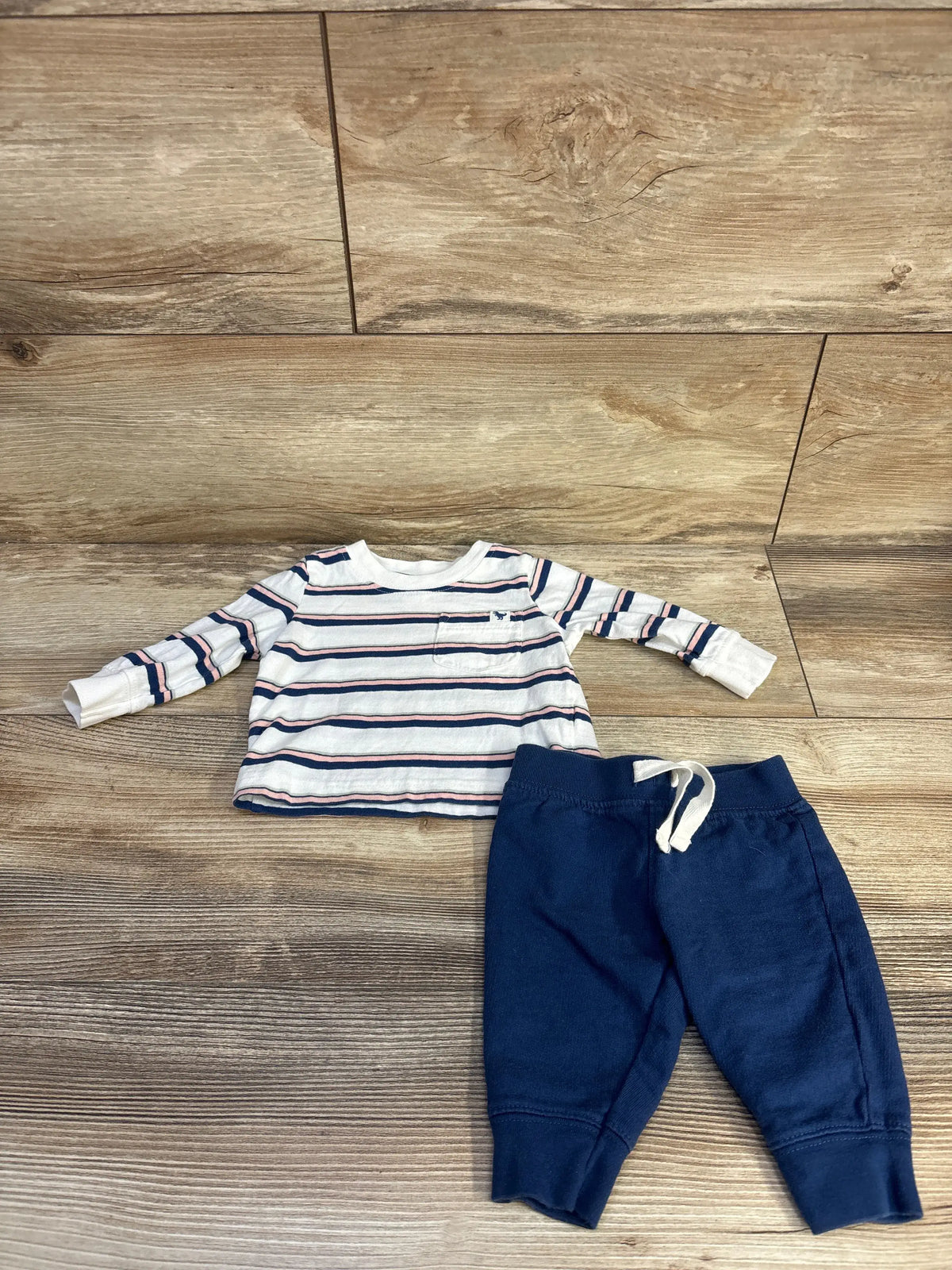 Overhead view of Just One You two-piece striped shirt and pants set showcasing long sleeves and drawstring pants on a wood-look floor