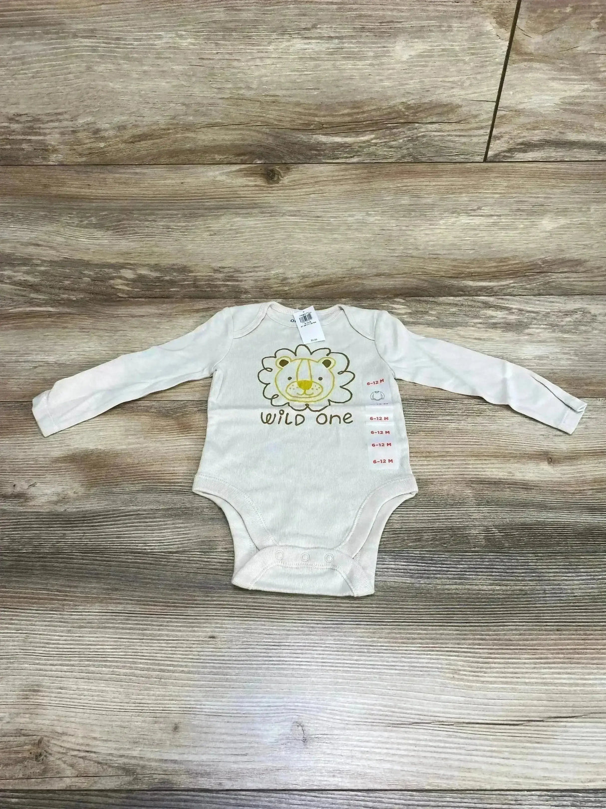 Flat lay of beige Old Navy bodysuit 6-12m showcasing lion graphic and Wild One text on wood floor