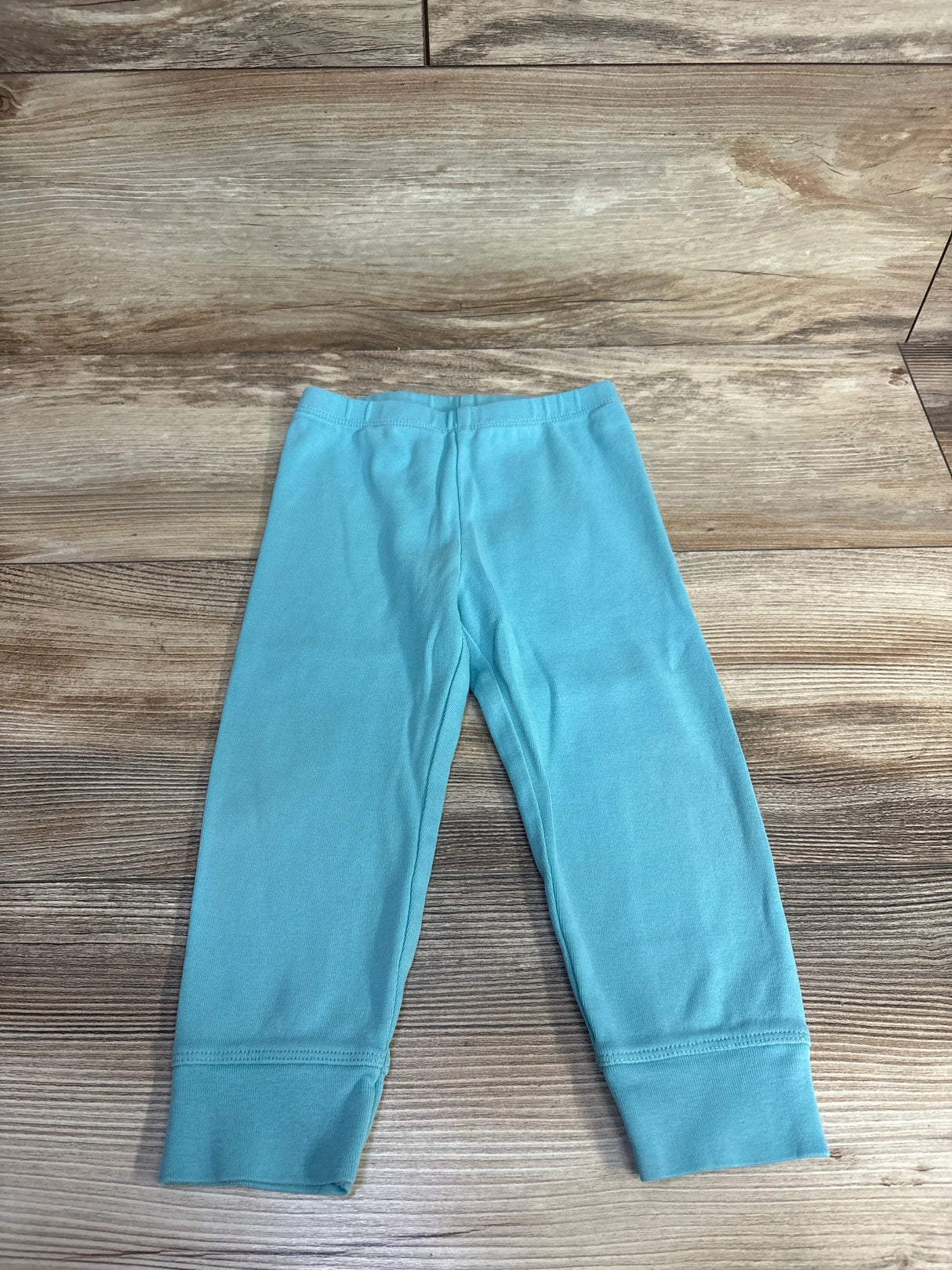 Light blue baby leggings on wood floor background