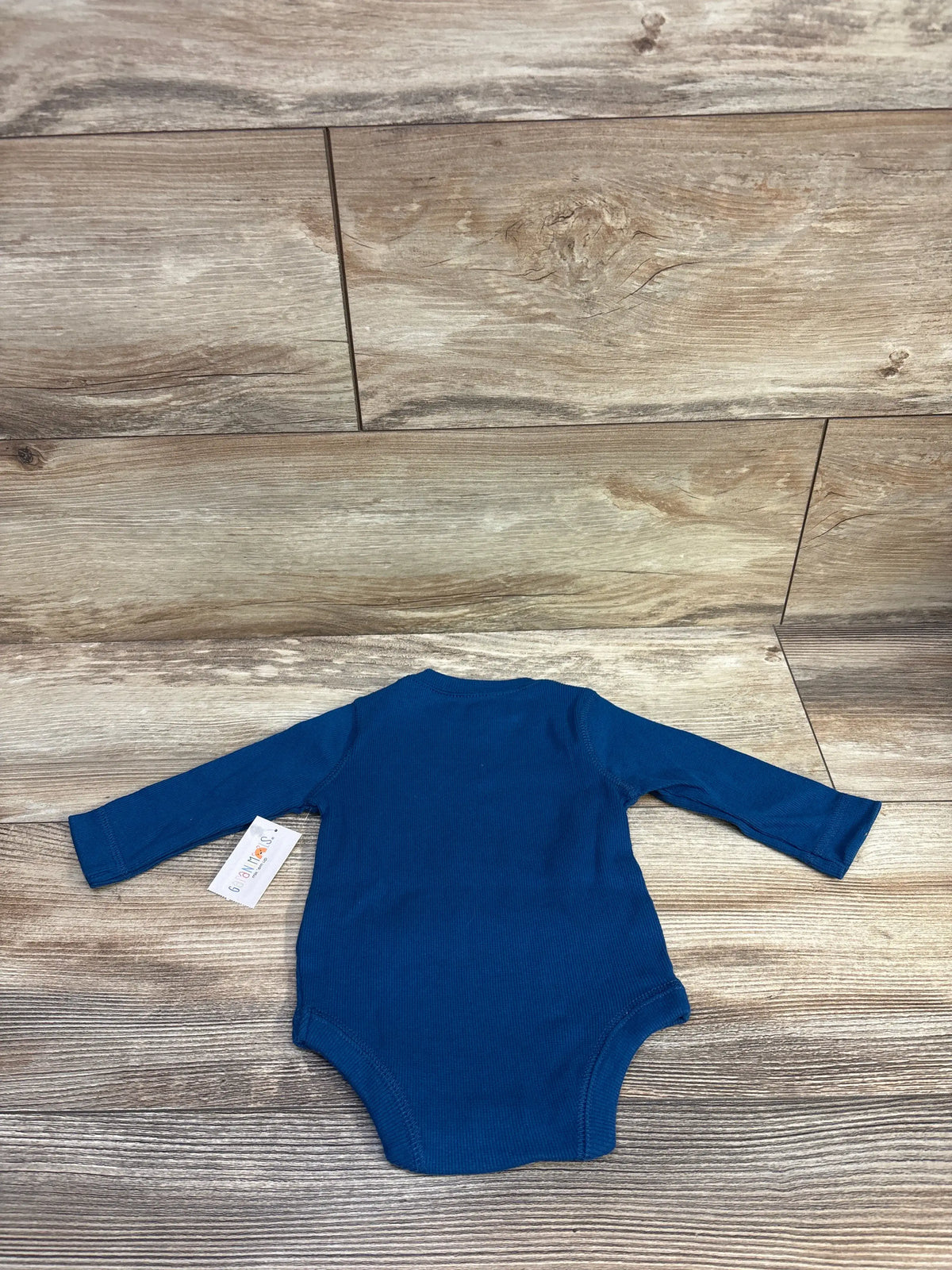 Back view of Garanimals ribbed long sleeve blue bodysuit size 0 to 3M showing ribbed texture and snap closure on wood background