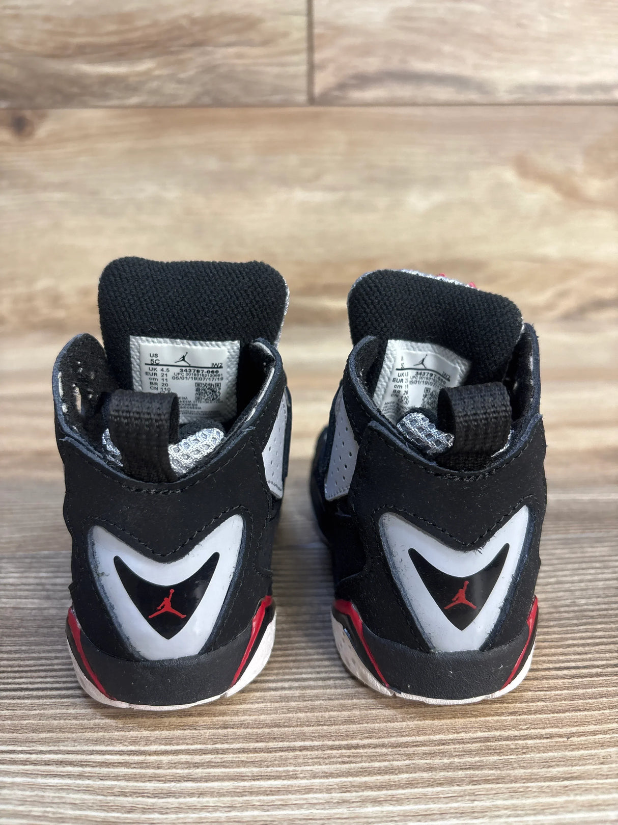 Rear view of Air Jordan True Flight TD toddler sneakers showcasing red Jumpman heel logo on wood floor