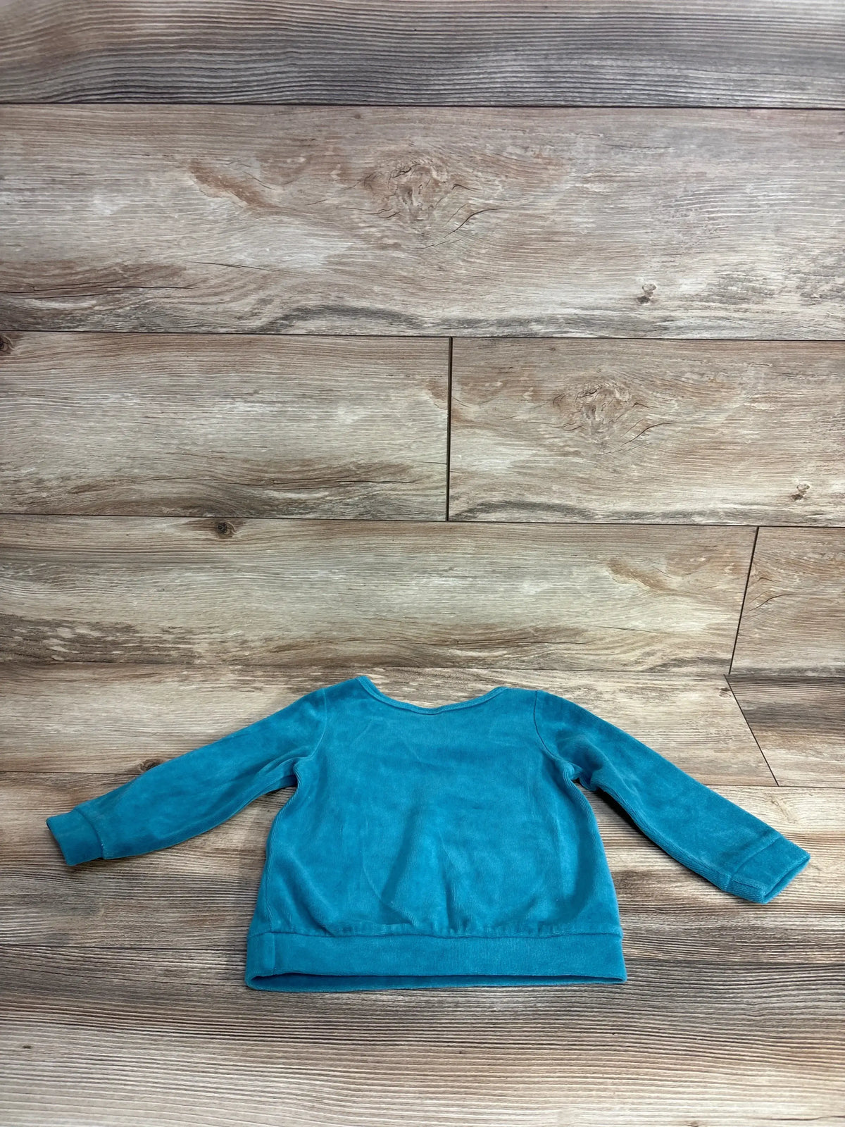 Flat-lay of teal First Impressions terry cloth toddler sweatshirt (18 months) showing long sleeves and crew neck on wood background