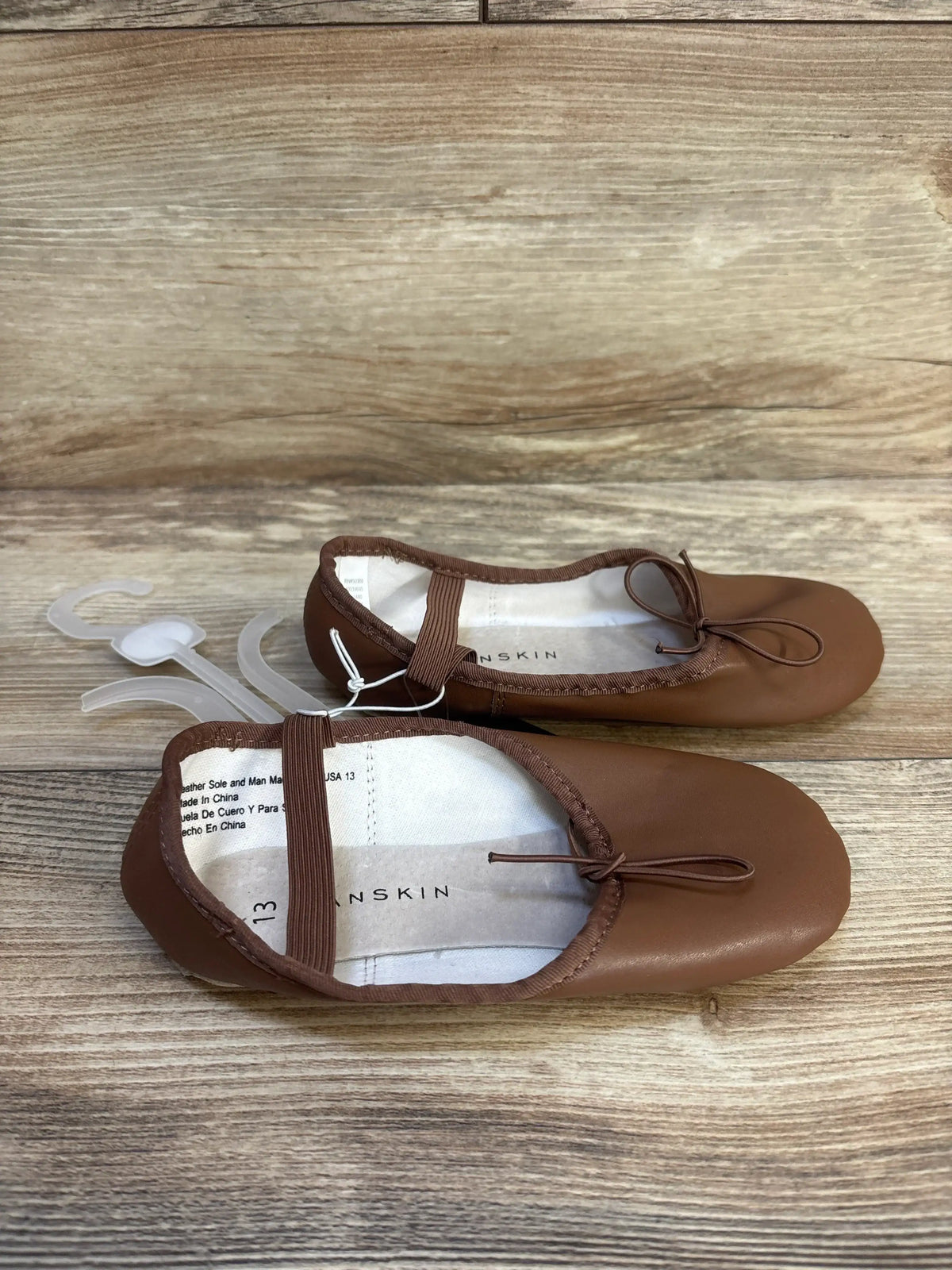 Brown toddler ballet flats with bow detail on wooden background
