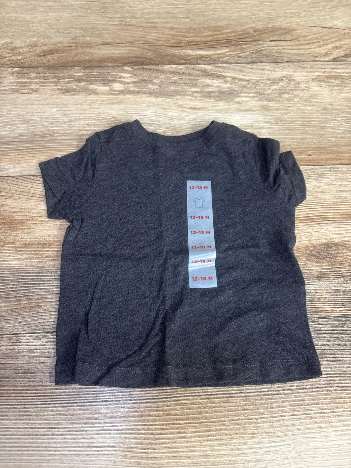 Dark gray baby t-shirt size 12-18 months on wooden surface