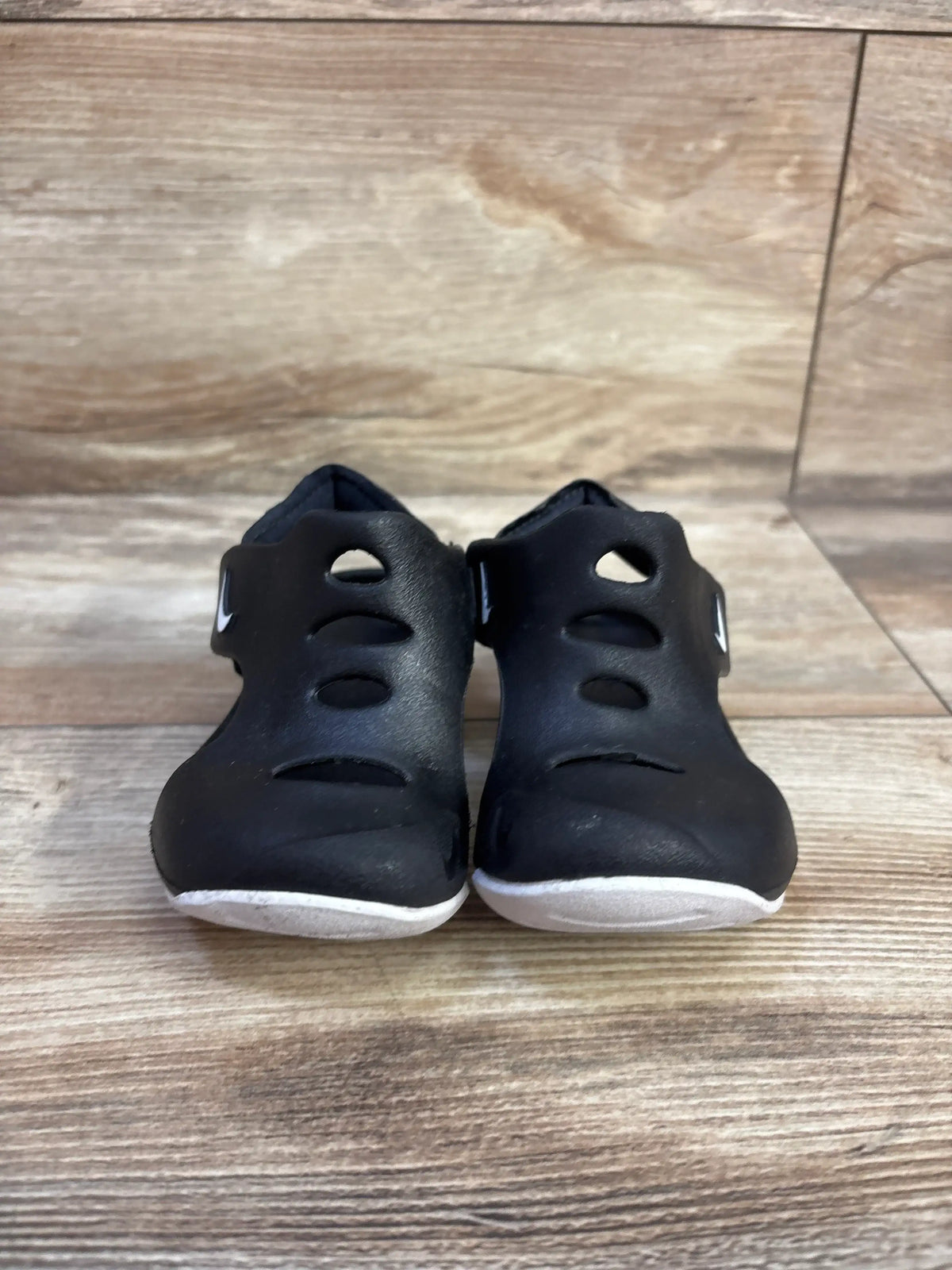 Front view of Nike Sunray Protect 3 TD water shoes in black with white soles, cutout vents and side strap on wooden floor