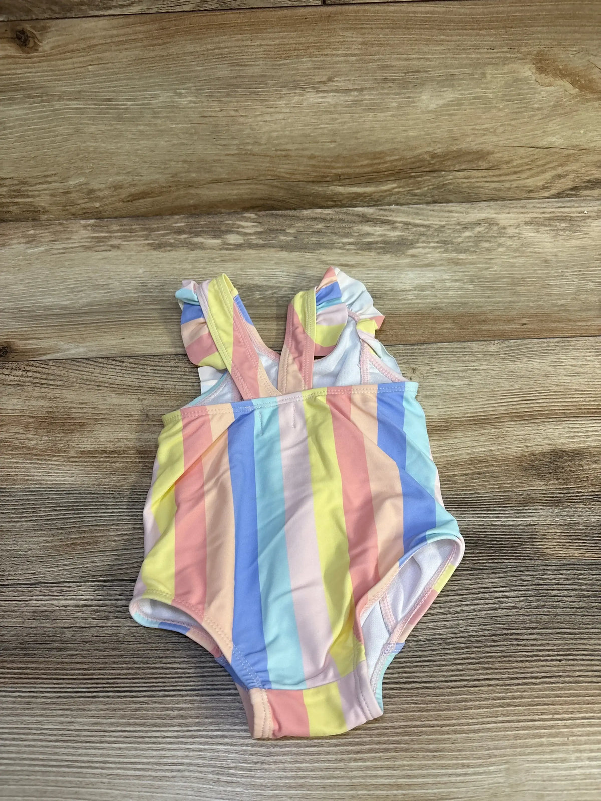 Front view of Starting Out 1pc striped swimsuit in pink, size 9m, showcasing ruffle sleeves on a wood-grain background