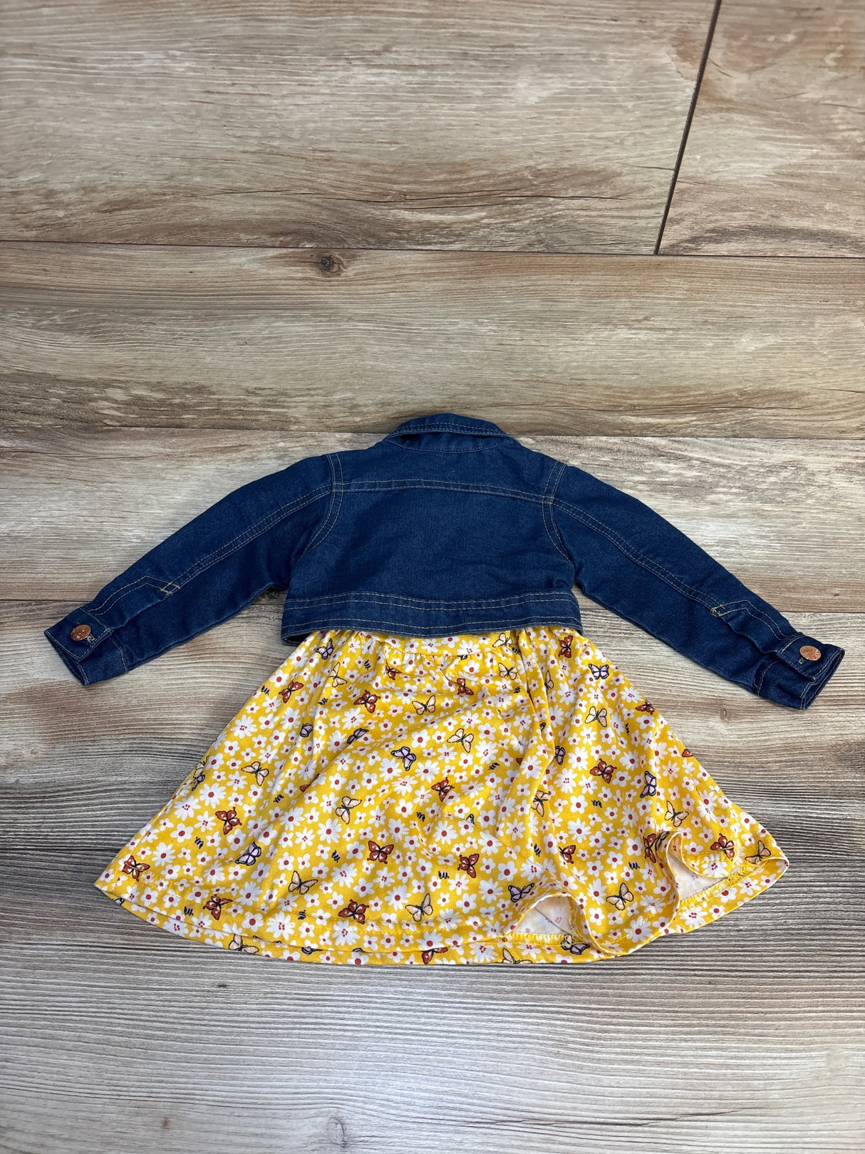 Kids denim jacket with yellow floral butterfly dress laid flat on wood background