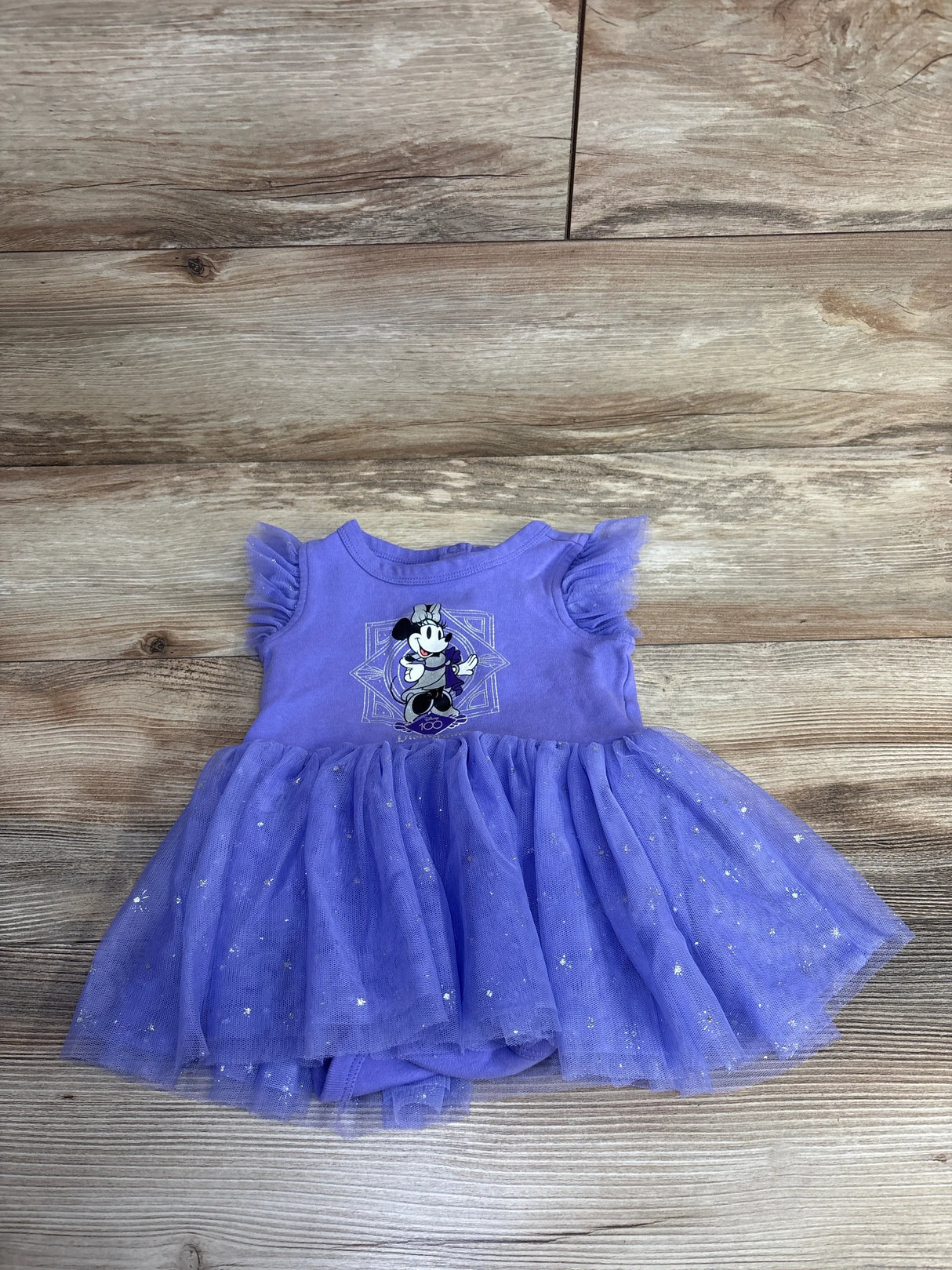 Purple toddler dress with tulle skirt and cartoon character, wood background